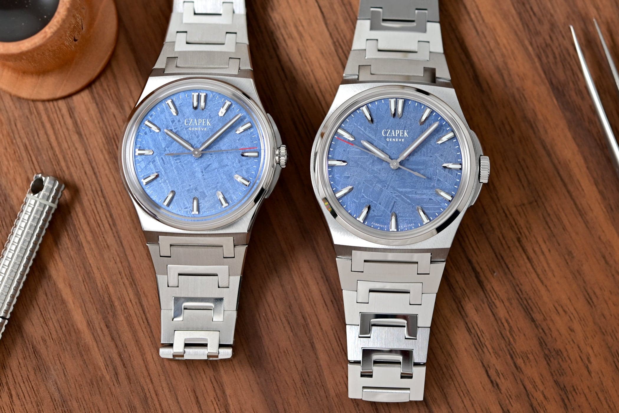 The two Czapek Antarctique Frozen Meteor editions side by side on a wooden tray, 38.5mm and 40.5mm steel cases with blue-lacquered Gibeon meteorite dials, faceted applied indices and V2 integrated bracelets with polished C-shaped centre links
