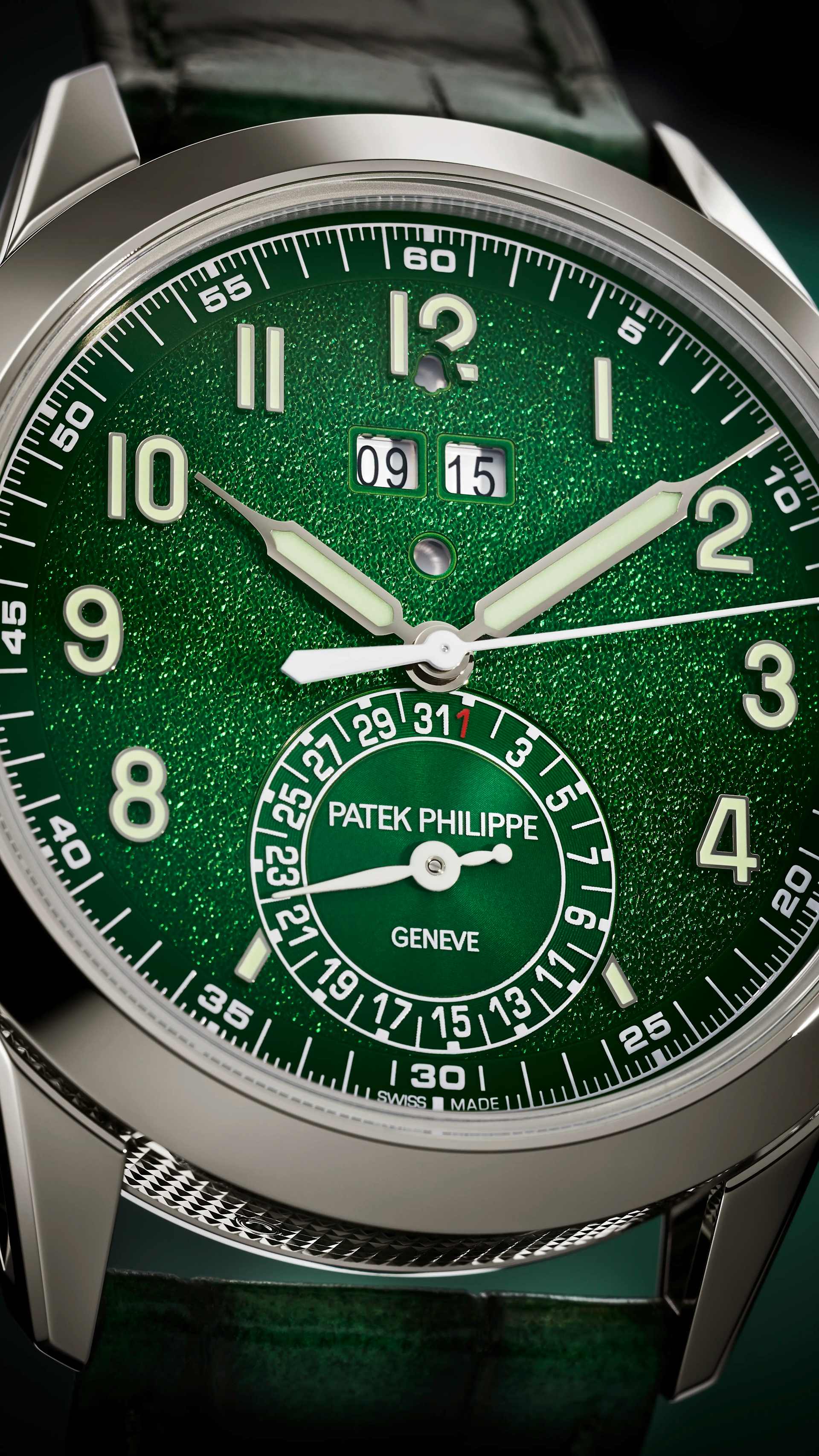 Dial macro of the Patek Philippe 5322G-010, green grainy gradient with applied white gold Arabic numerals, double aperture at 12 showing the programmed alarm time, bell-shaped day\/night window beneath, small date sub-dial at 7 with PATEK PHILIPPE GENEVE signature and small red 31 marker