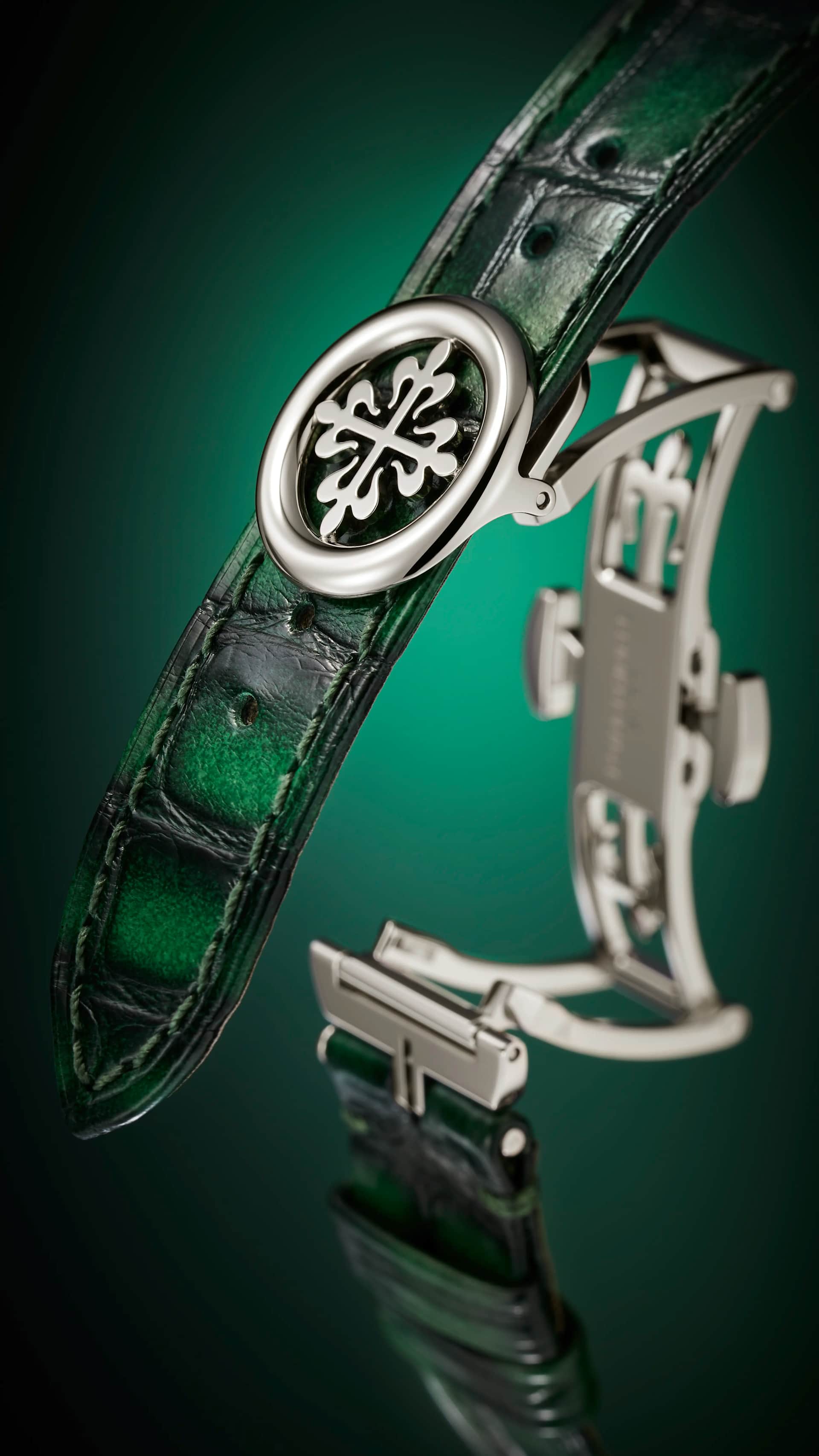 Patek Philippe three-fold deployant clasp with the Calatrava cross relief, shown on the green calfskin strap with fabric pattern and contrasting beige stitching