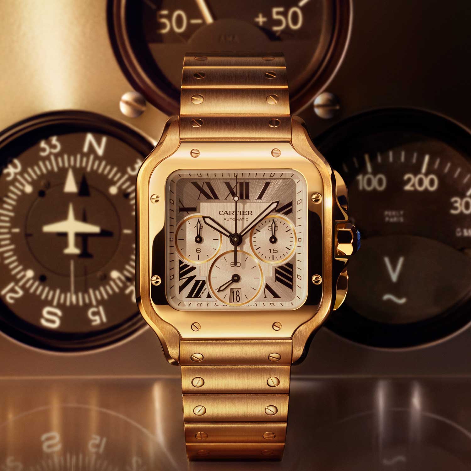 Yellow gold Cartier Santos Chronograph XL 2026 with silver sunburst dial and gold-bordered subdials, shown against blurred vintage aircraft instruments including a compass and airspeed indicator