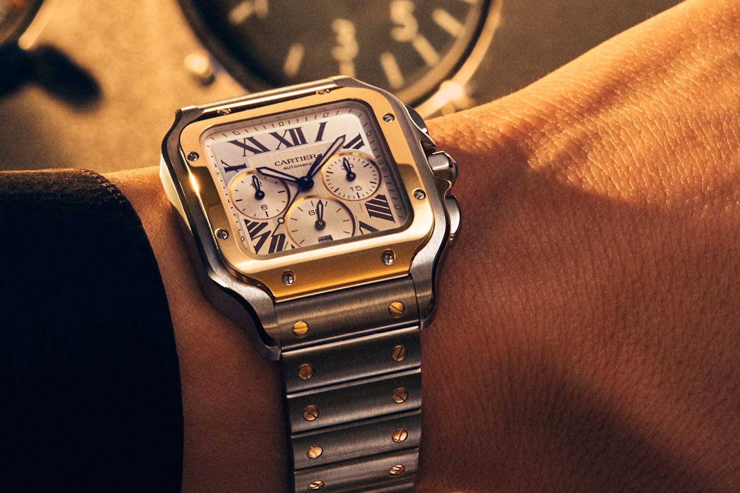 Two-tone steel and yellow gold Cartier Santos Chronograph XL 2026 on a wrist, showing the gold bezel, silver sunburst dial with rhodium subdial borders and interchangeable steel and gold link bracelet