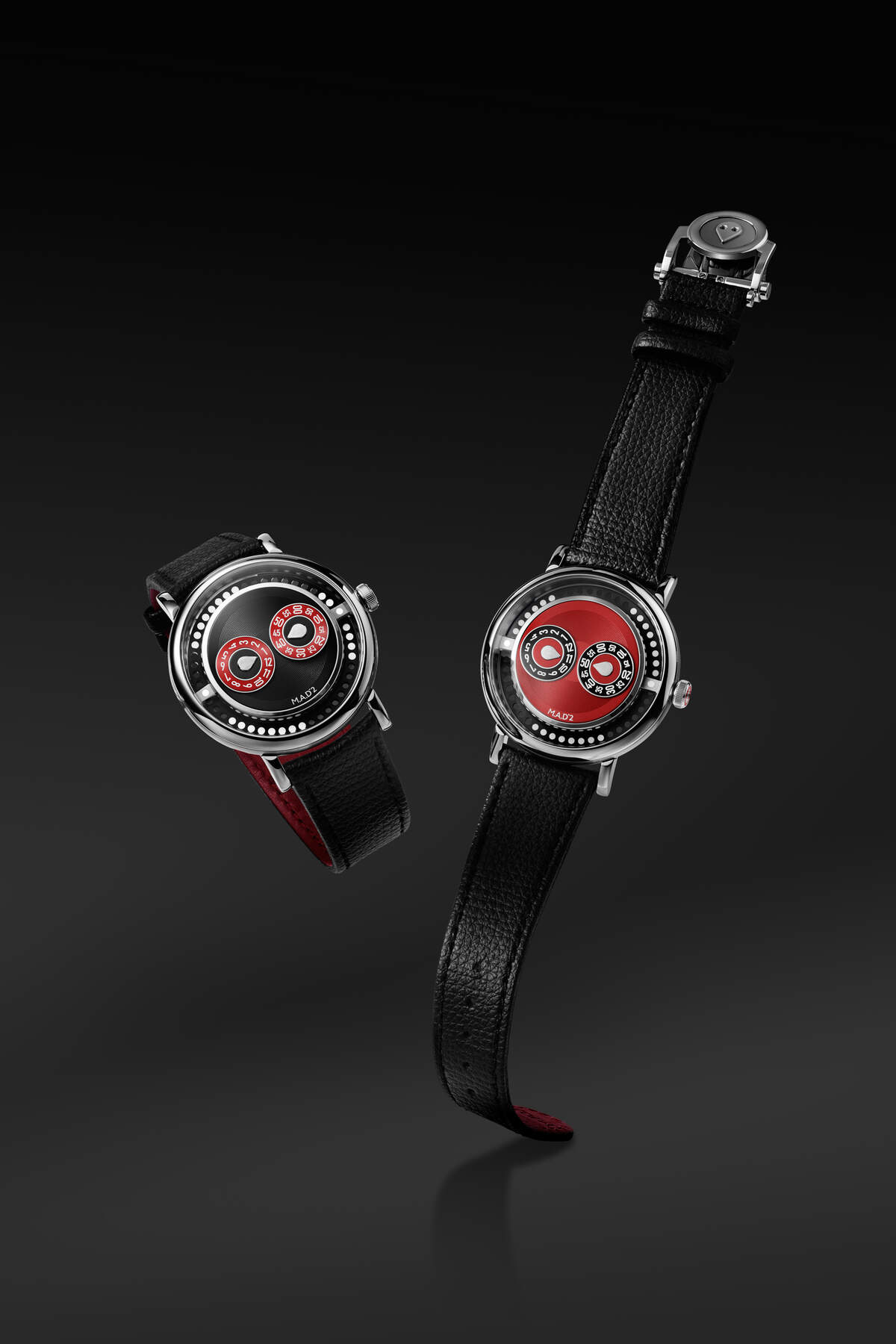 Two MB&F M.A.D.2 watches shown together against a black background, the R&B on the left with black dial and red sub-dials, the REDemption on the right with red dial plate and black hour and minute discs, both on black leather straps with red inner lining