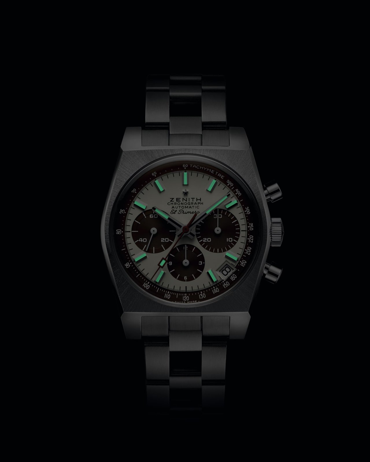 Lume render of the Zenith Chronomaster Revival A384 Tropical against a black background, the applied indices and chronograph hands glowing green from the Super-LumiNova fill, the brown sub-dials and tachymeter rehaut visible behind the lume, on the integrated steel ladder bracelet