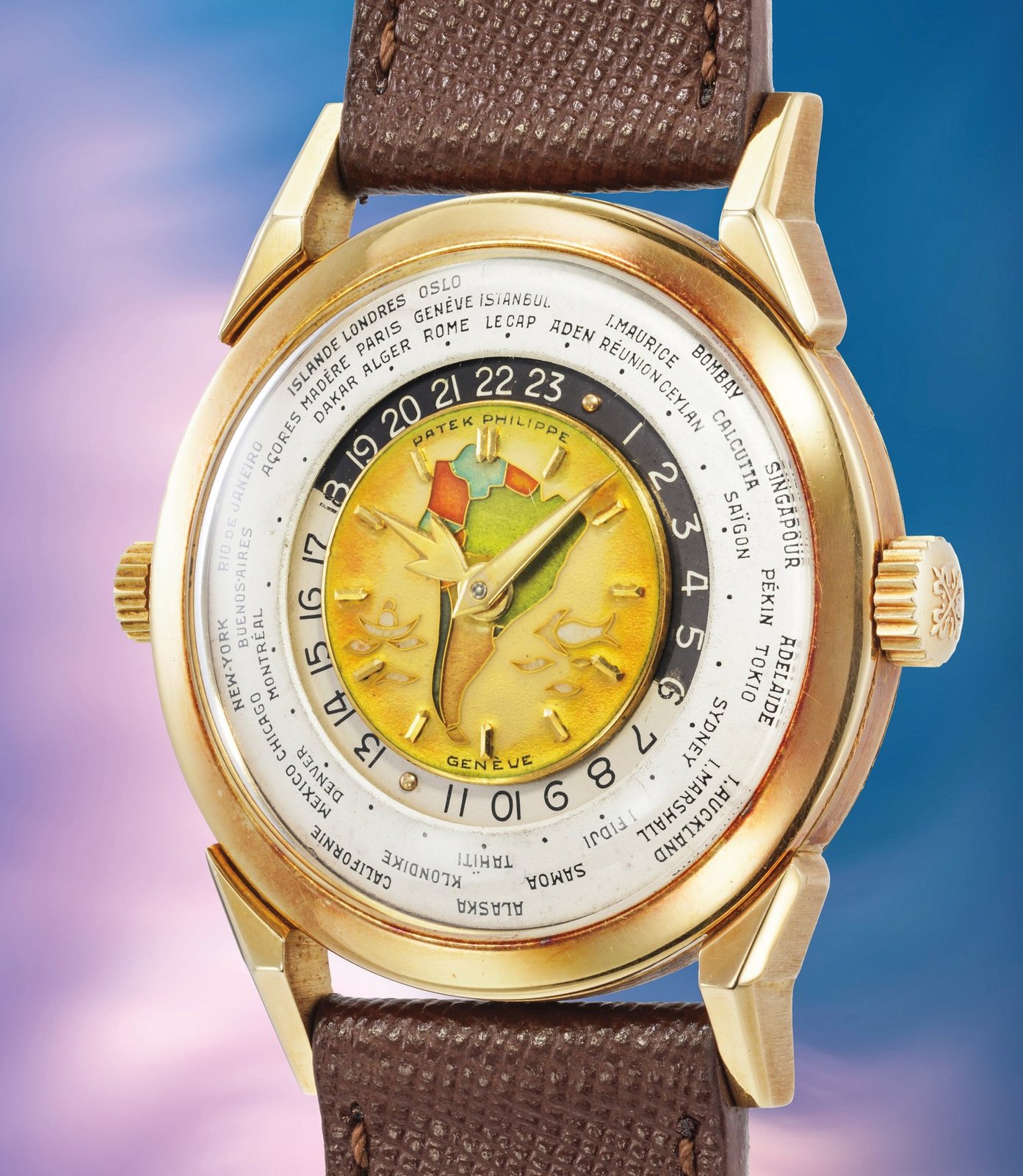 Patek Philippe reference 2523 'Doppia Corona Policromo' in 18k yellow gold, 36mm two-crown world-time wristwatch from 1953, with cloisonné enamel dial depicting the map of South America in green, yellow and orange tones, applied yellow gold hour markers, gold dauphine hands, outer rotating city ring with names including New York, Paris, Geneva and Tokyo, on a brown leather strap with yellow gold pin buckle
