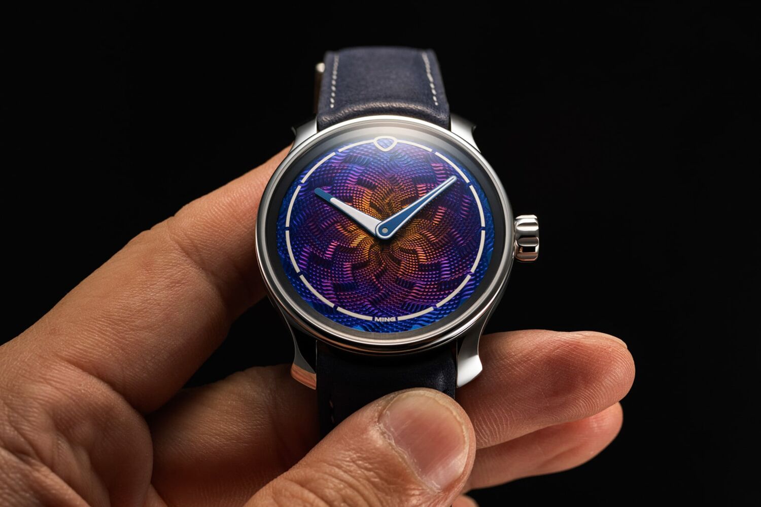 Ming x J.N. Shapiro 37.06 Lightning held in the hand, 38mm steel case, with a titanium dial cut in a lightning guilloche pattern and heat-coloured from an orange and yellow centre through purple to deep blue at the edge, blued hands, MING signature at six o'clock, on a blue calfskin strap