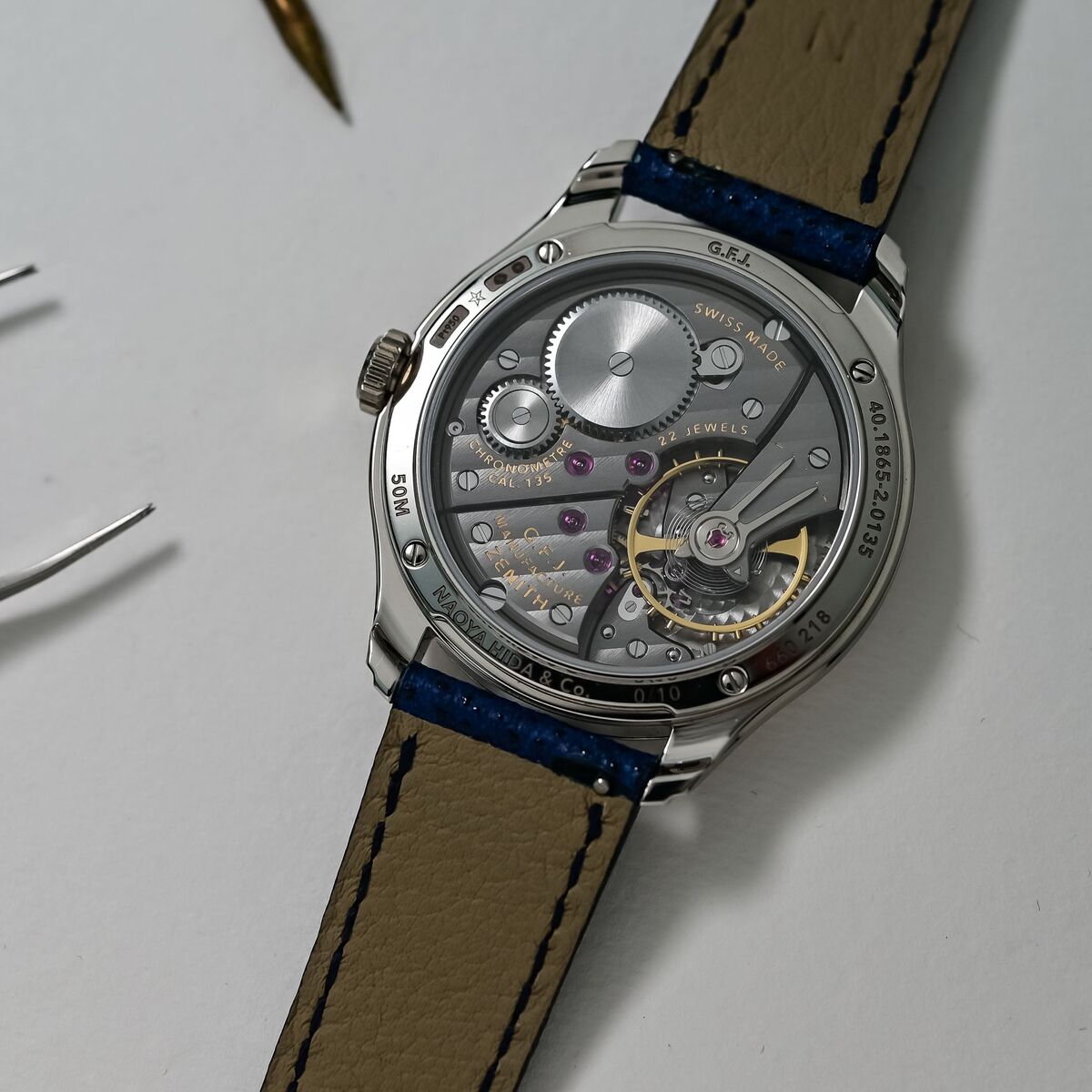 Caseback view through the sapphire showing the Calibre 135 marked CHRONOMETRE CAL.135, the oversized balance and gold-coloured regulator, with G.F.J. MANUFACTURE ZENITH and NAOYA HIDA and Co. engraved around the rim and the edition number 0/10