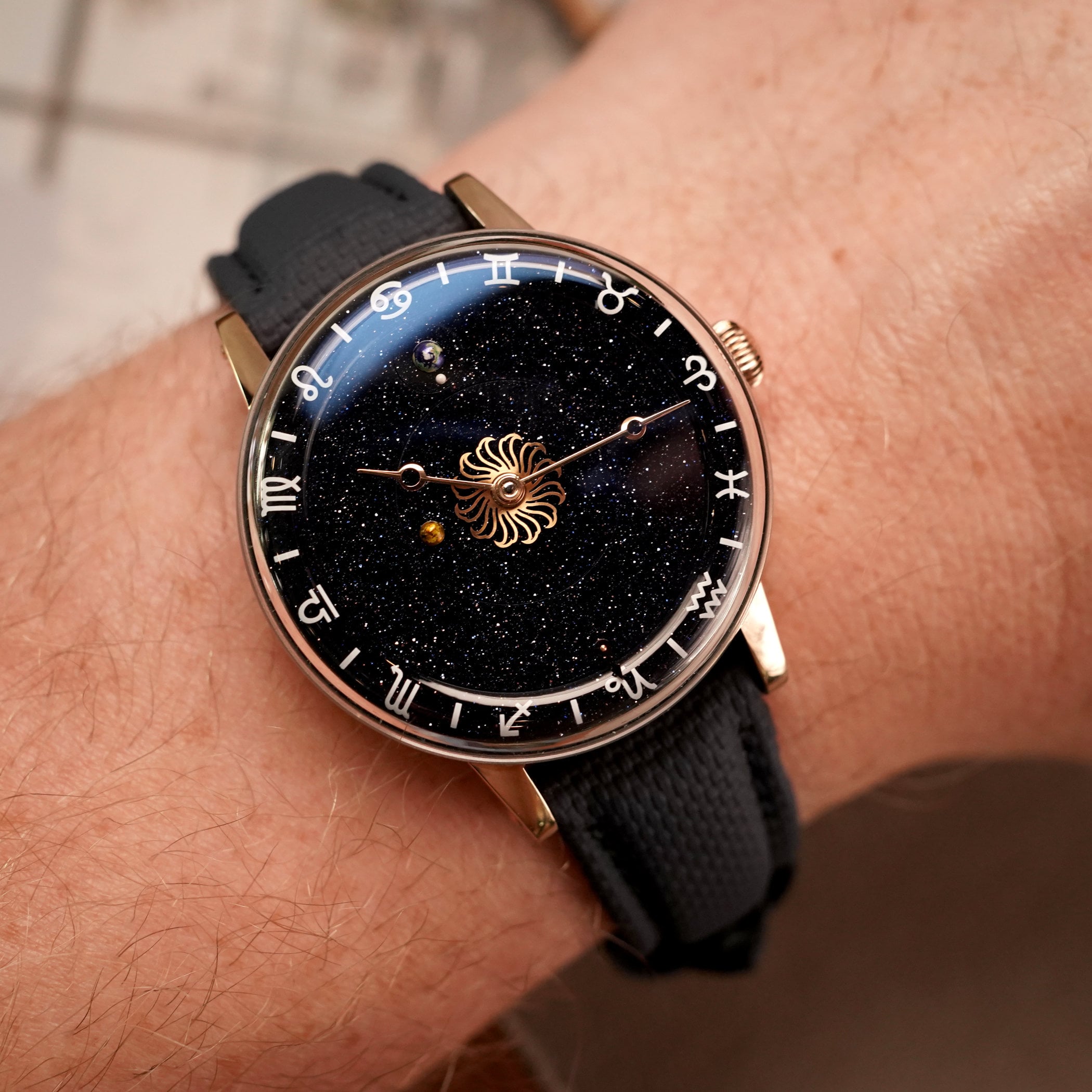 Venus Zodiac rose gold on the wrist, 38mm case with thin polished bezel, dark blue Sailcloth strap