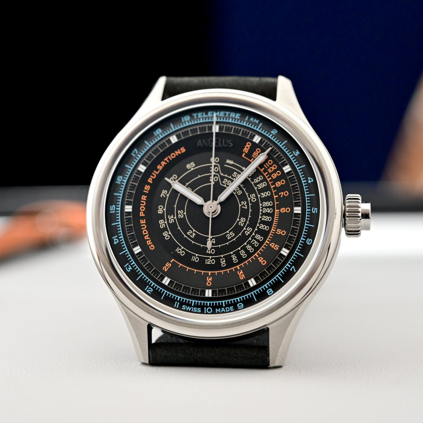 Ebony-black Instrument de Mesures ref. OCHDS.B01A.V1476S head-on, blue, orange and cream telemeter, pulsometer and spiral tachymeter scales across a multi-level dial with syringe hands, on a black calf strap