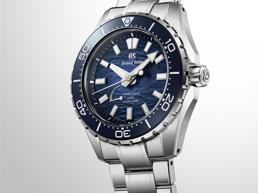 Macro of the SLGB023 blue Ushio dial, wave-textured gradient with applied faceted indexes, GS logo at twelve and the Spring Drive U.F.A. Diver's 300m text above a dial-side power reserve indicator near six