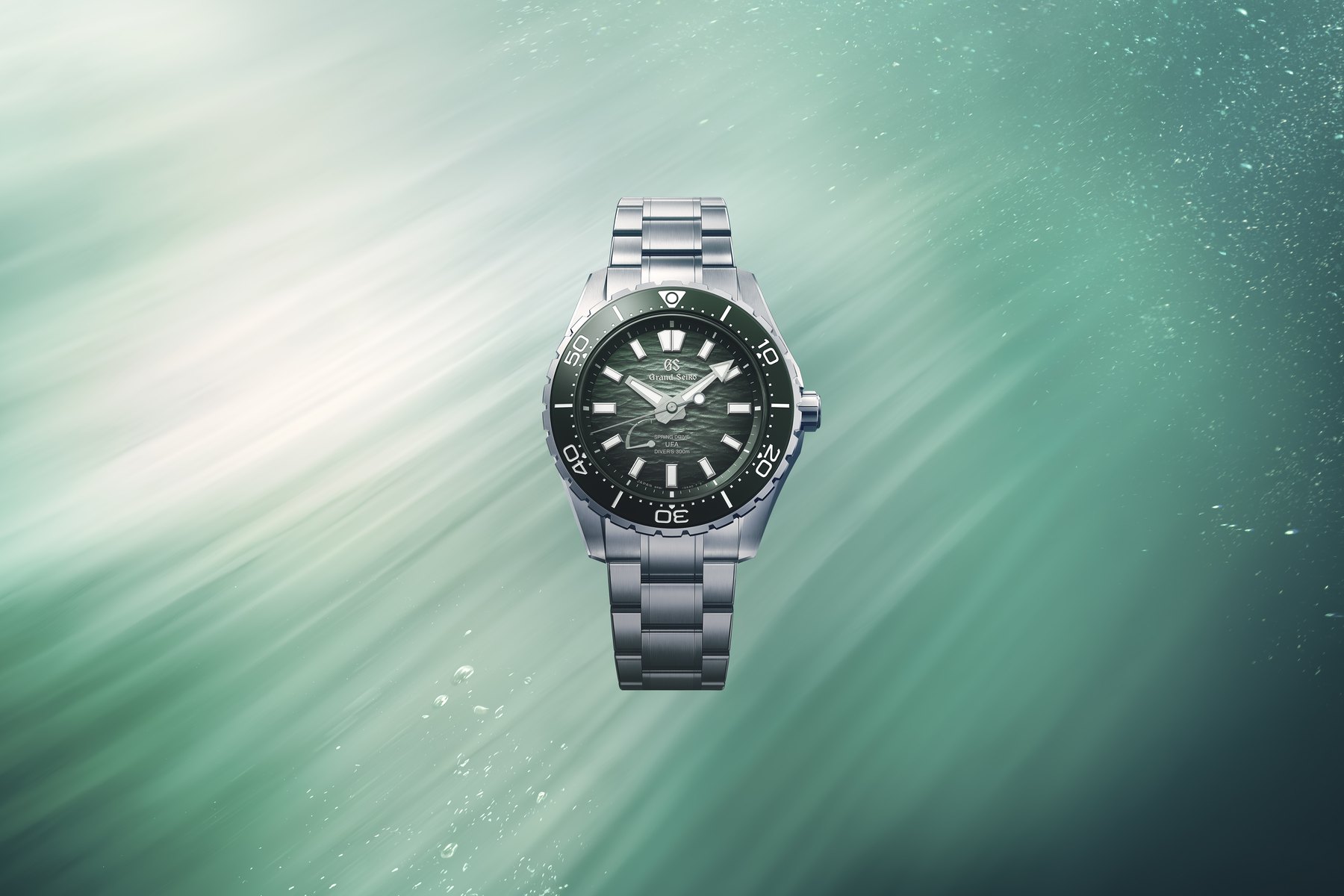 The sibling Grand Seiko SLGB025 with a green Ushio gradient dial and green bezel, shown against a green sunlit underwater background