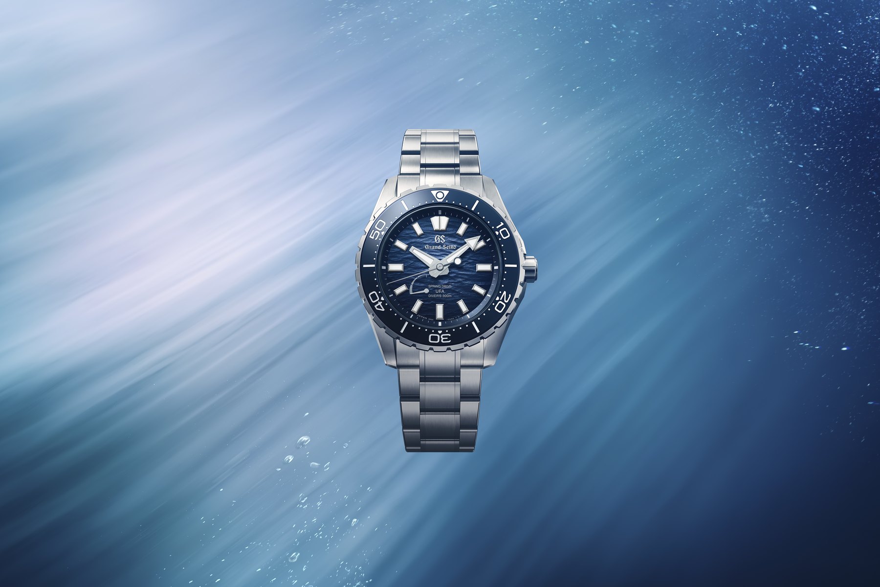 Grand Seiko Evolution 9 Spring Drive U.F.A. Ushio 300 Diver ref. SLGB023, blue gradient Ushio-textured dial, blue bezel, High-Intensity Titanium case and bracelet, shown against a sunlit underwater background