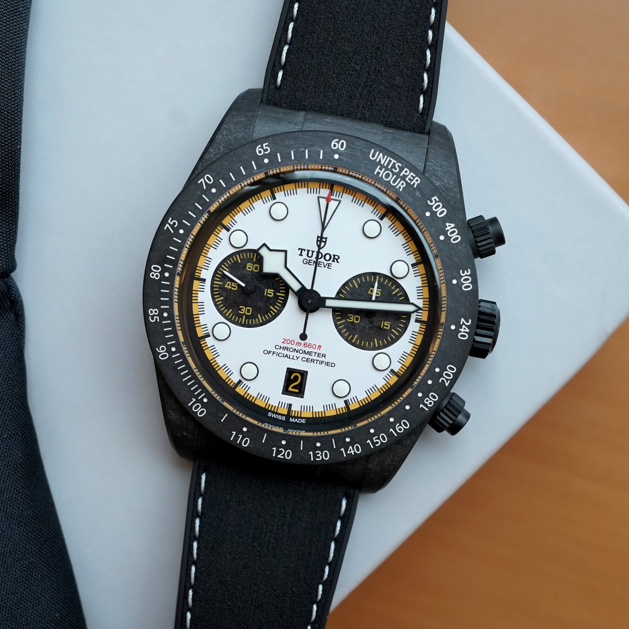 The Tudor Black Bay Chrono Carbon 26 at a three-quarter angle, marbled carbon-fibre case and tachymeter bezel, racing-white dial with yellow minute track, two black carbon-fibre sub-counters and the yellow date window at six