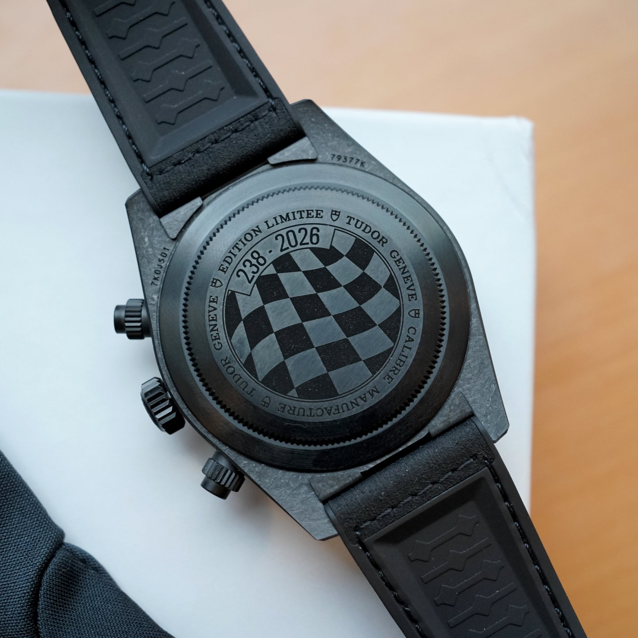 The titanium caseback of the Carbon 26 engraved EDITION LIMITEE 238-2026 around a checkered-flag motif and the reference 79377K, on the black tyre-pattern strap