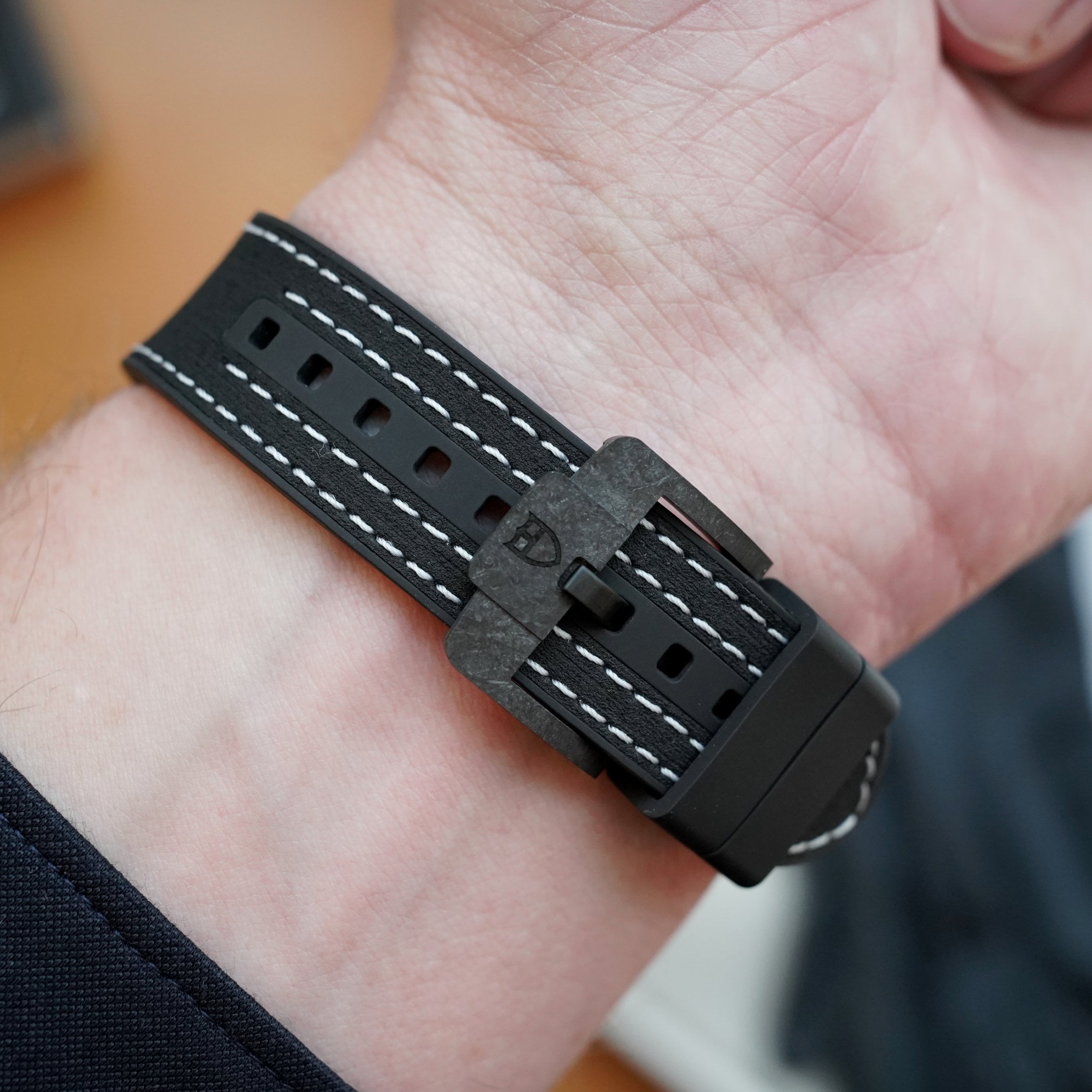 Wrist shot of the hybrid leather-rubber strap with its rubber tyre tread and the blackened pin buckle stamped with the Tudor rose