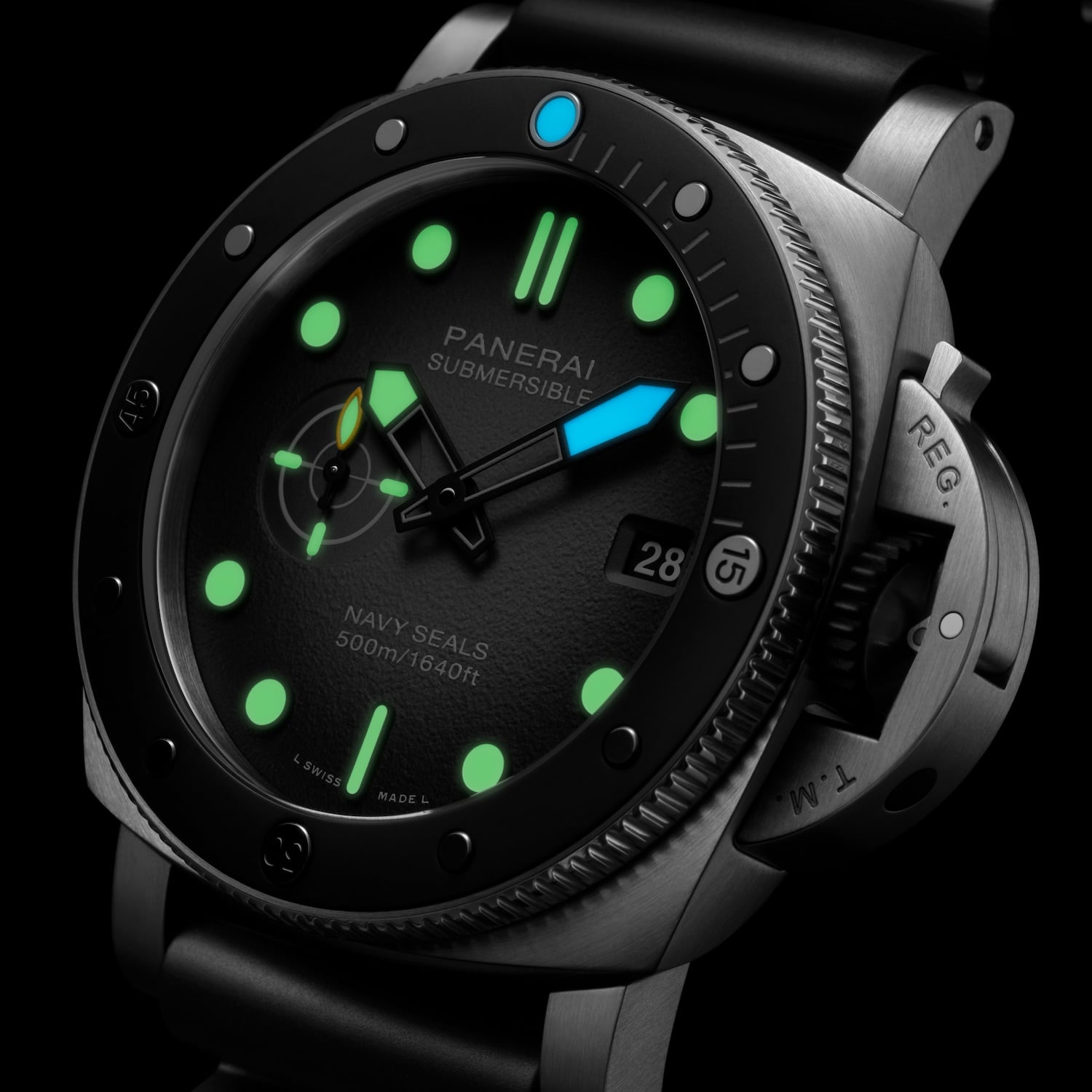 Macro three-quarter view of the Panerai Submersible Navy SEALs PAM01738 in the dark, green Super-LumiNova on the indices and small-seconds counter and blue luminescence on the minute hand and noon bezel dot, with the date at 3 and crown-protecting lever