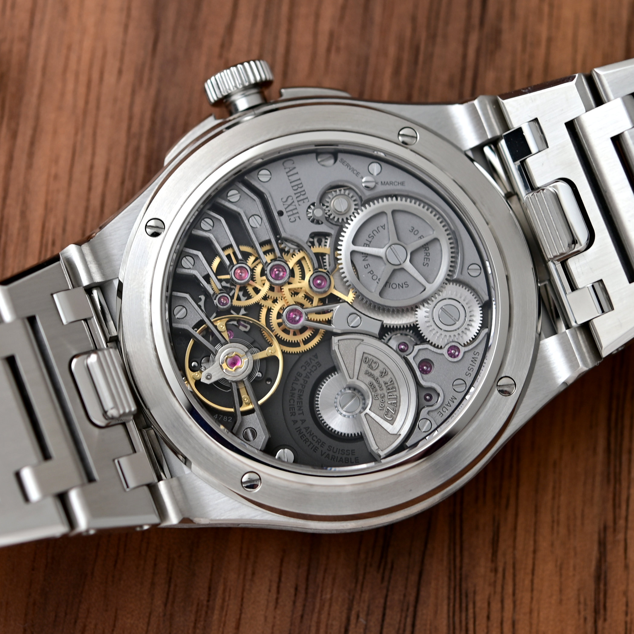 Caseback of the Czapek Antarctique Frozen Meteor with CALIBRE SXH5 printed on the sapphire, seven black openworked sandblasted bridges over gilded gears, the variable-inertia balance and the recycled-platinum micro-rotor signed Czapek & Cie