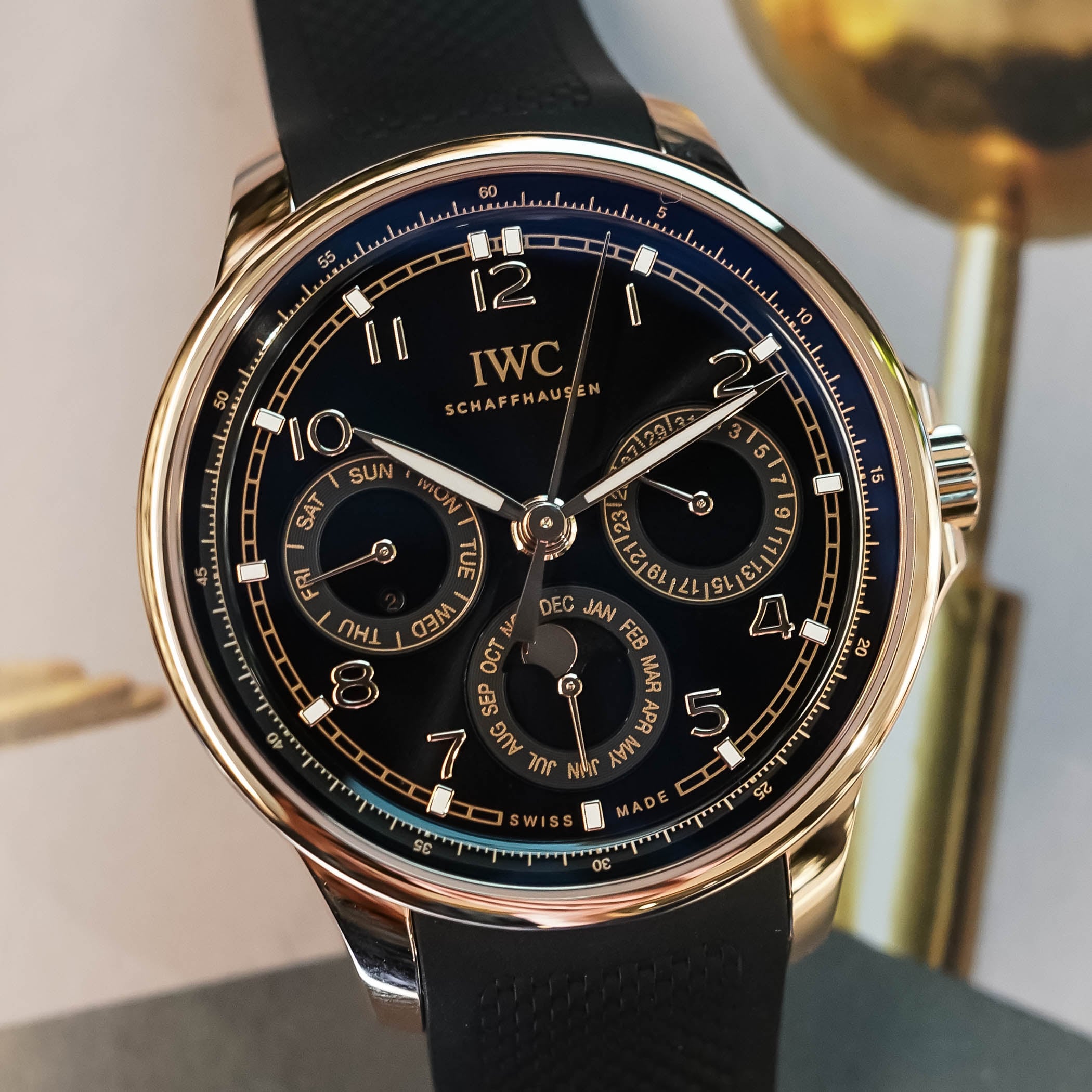 Dial macro of the IWC Portugieser Yacht Club Perpetual Calendar IW344101, the gold-ringed day counter at nine, date counter at three and month ring with moon-phase aperture at six against layered black lacquer, with applied gold Arabic numerals
