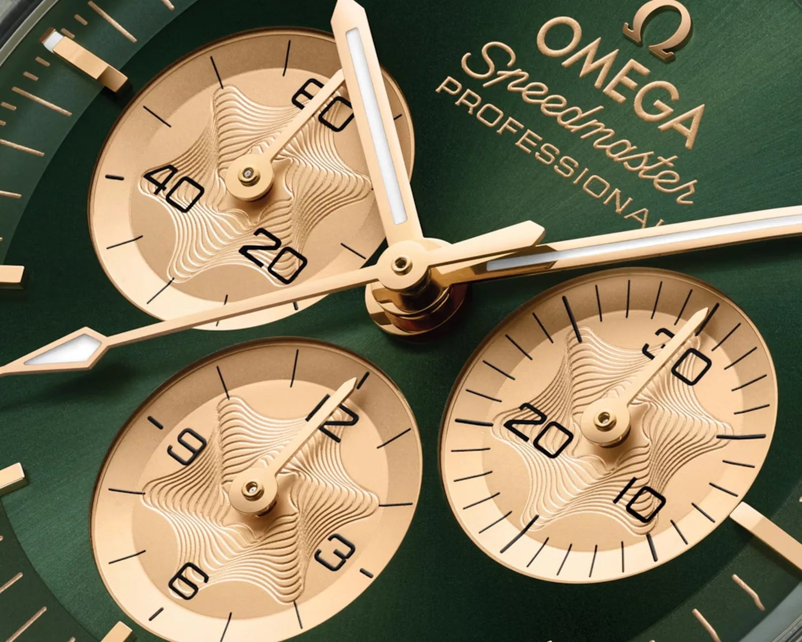 Macro of the Moonshine gold subdials on the green dial of the Speedmaster 310.60.42.50.10.002, each counter stamped with the radial golf-spike azurage pattern, gold hands and applied Omega Speedmaster Professional script above
