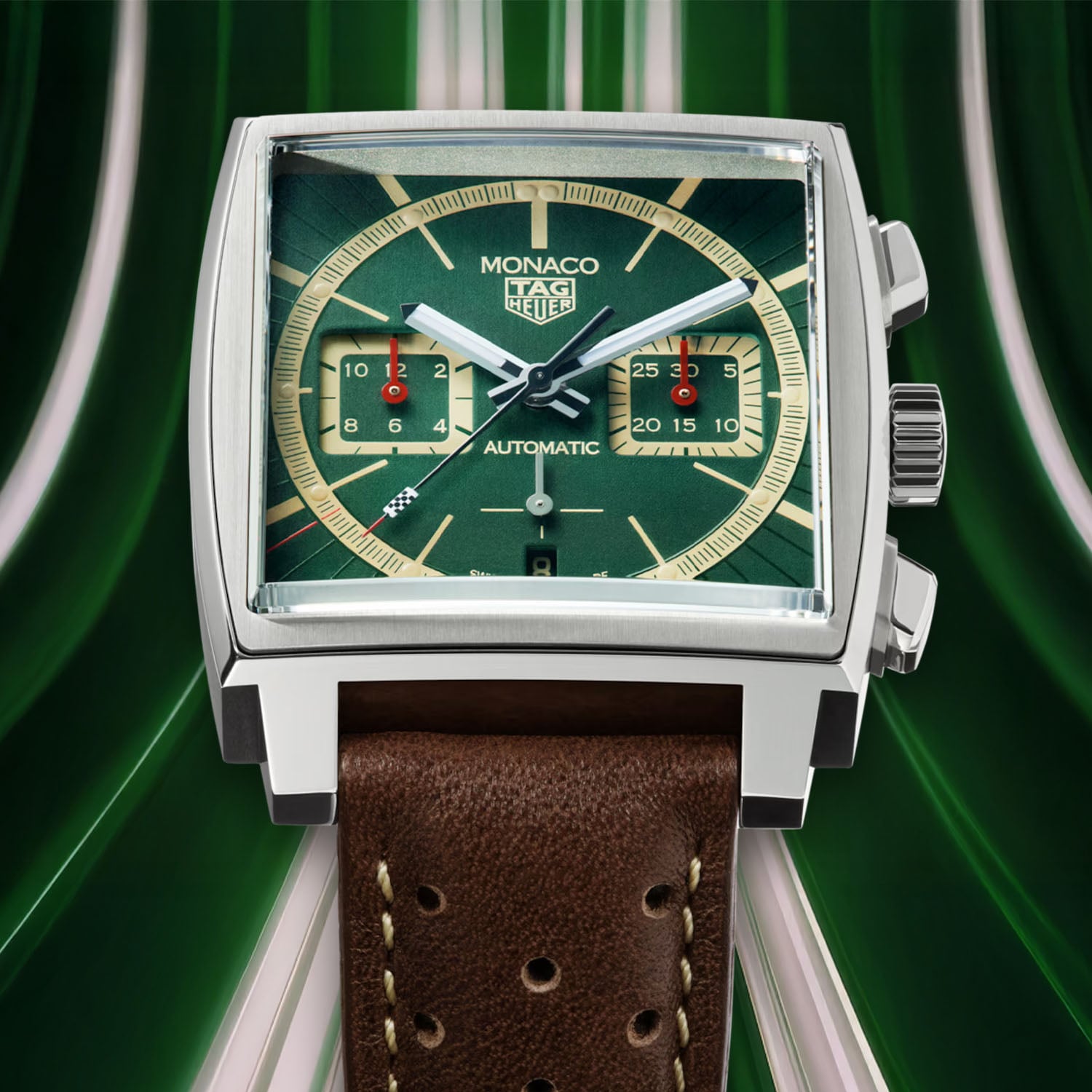 Dial close-up of the Monaco x Goodwood 2026, beige minute ring and counters over green sunray lacquer, chequered flag tip on the seconds hand, red record marking at 39 seconds and the date at six