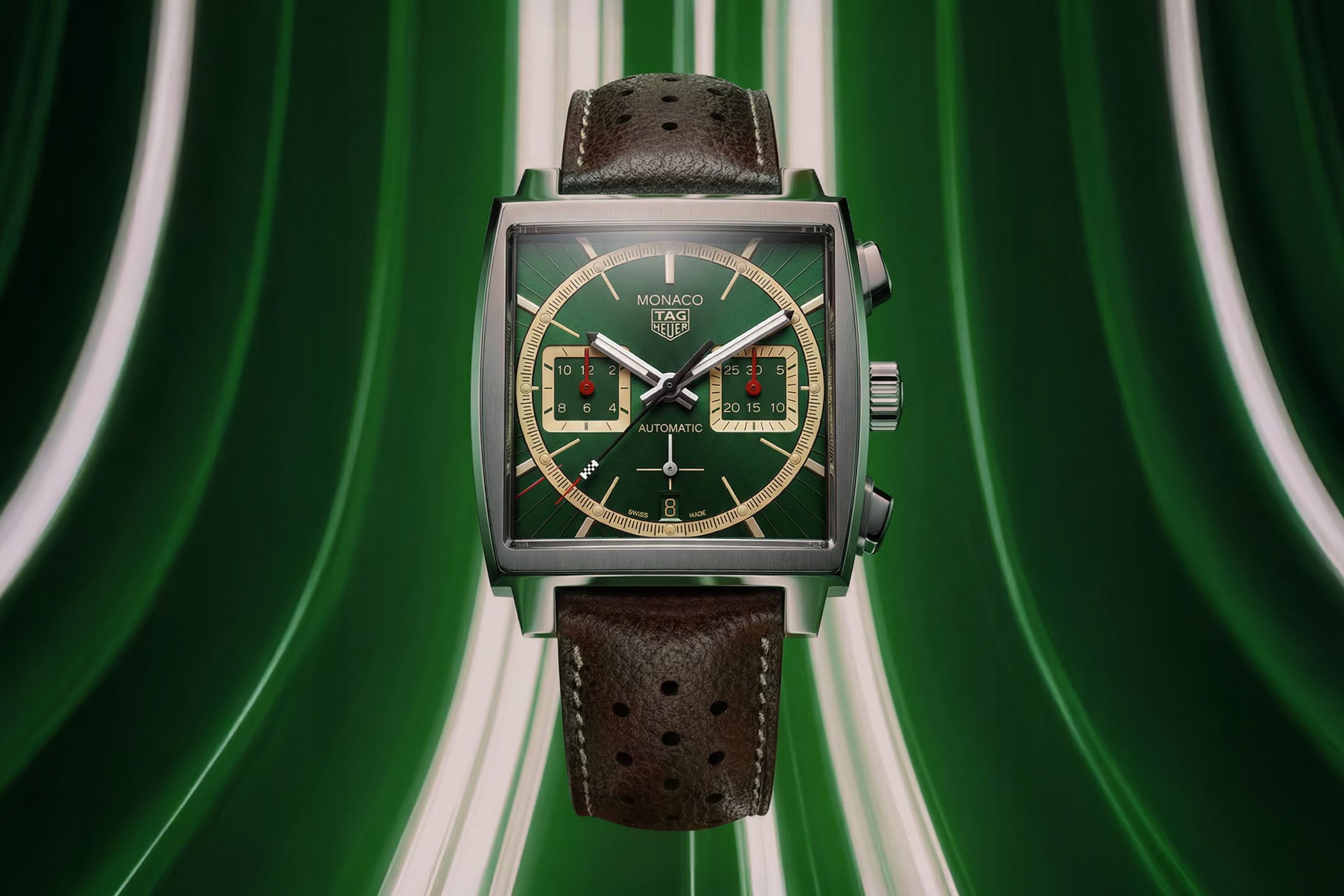 TAG Heuer Monaco Chronograph x Goodwood Festival of Speed 2026, ref. CBL211C.FC8392, square steel case with British Racing Green sunray dial, beige subdials and minute ring, red subdial hands and a brown perforated leather strap, shot against a green backdrop