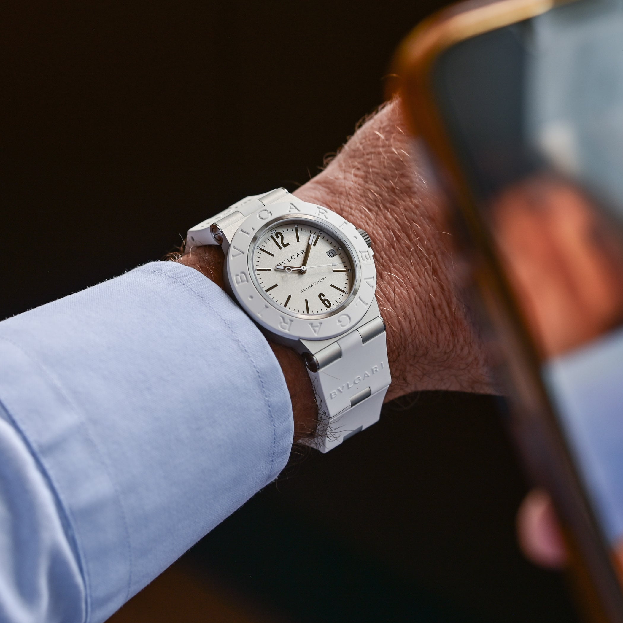 Bulgari Aluminium White ref. 104335 on the wrist under a light blue shirt cuff, opaline white dial with rhodium-plated hands and indices, white rubber bezel engraved Bvlgari Bvlgari and white rubber strap