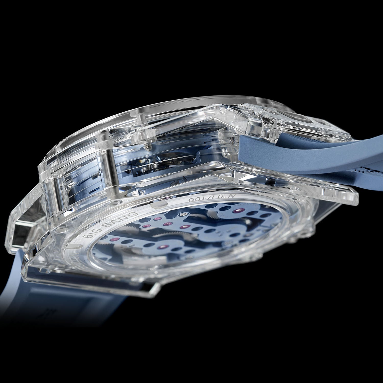 Side and caseback view of the sapphire case with BIG BANG and N°01/100 engraved on the sapphire back, the sky-blue movement bridges and ruby jewels visible straight through the transparent case
