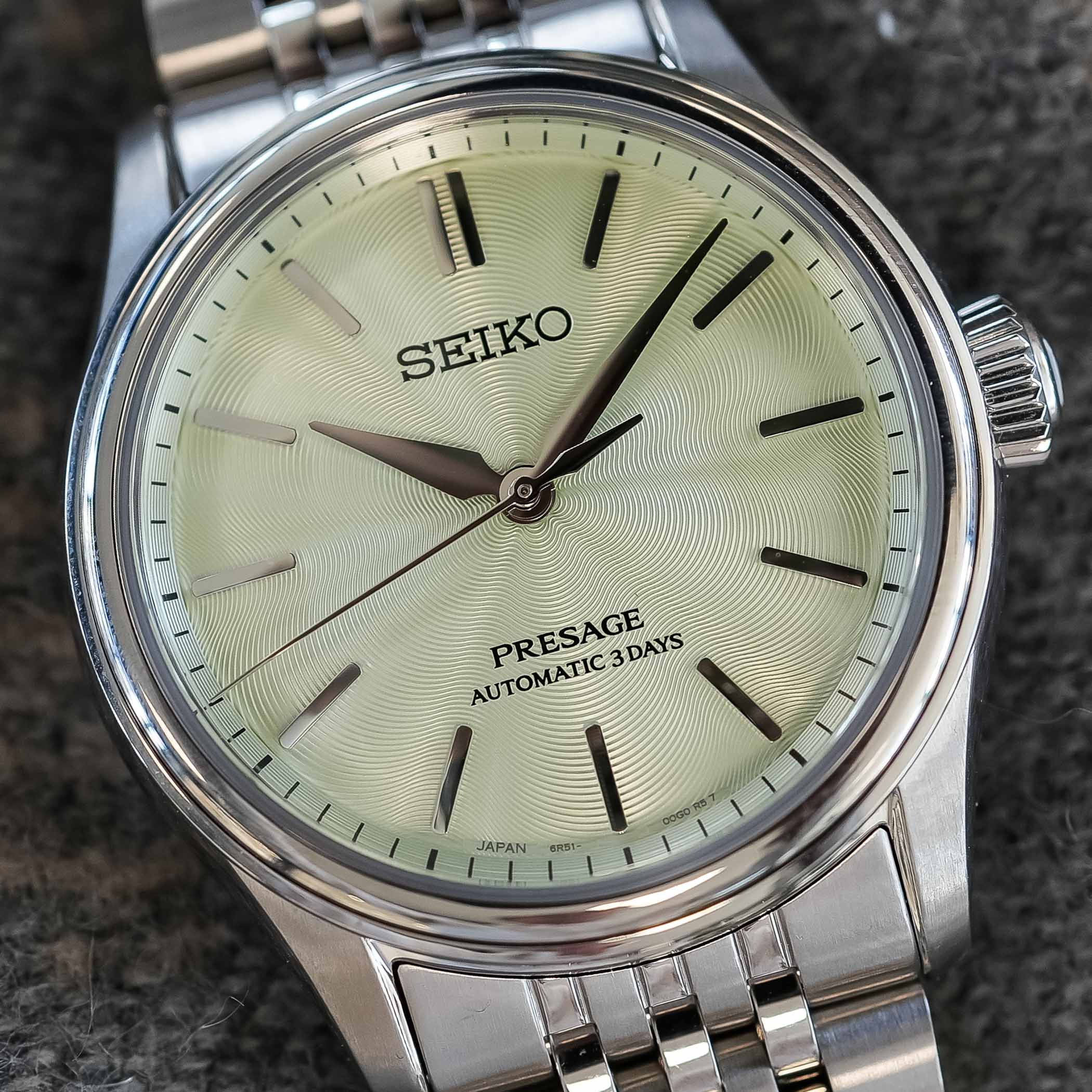 Macro of the HCC002 dial in wakatake-iro green, showing the stamped silk-inspired texture radiating from the centre in fine wavy lines, applied baton markers, printed SEIKO and PRESAGE AUTOMATIC 3 DAYS text and JAPAN 6R51 at the foot, in the polished steel case on its bracelet