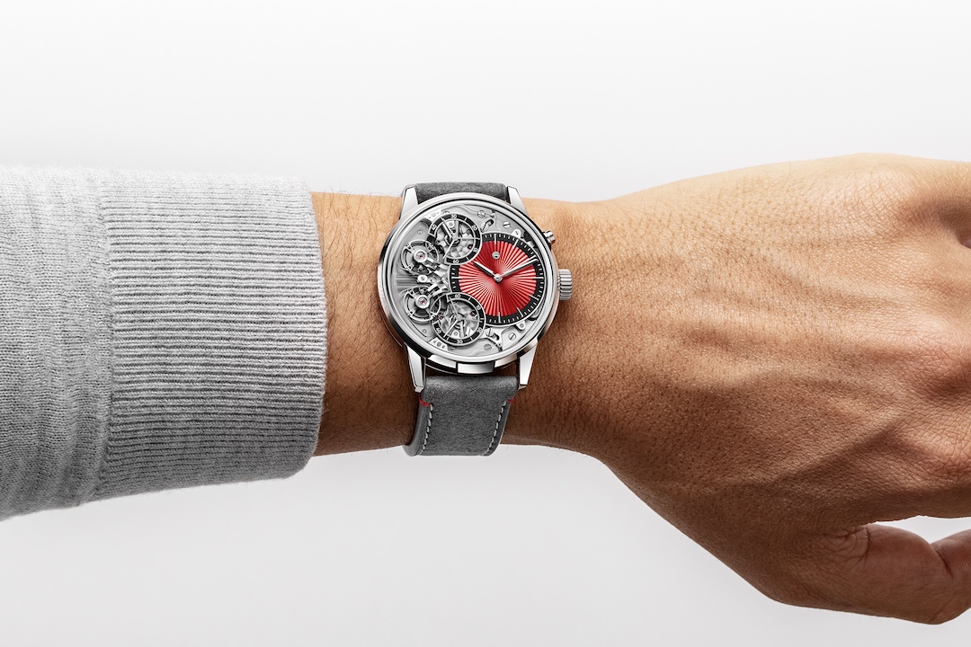 The Armin Strom Mirrored Force Resonance Red worn on a wrist below a grey sweater cuff, the red dial and polished case seen from above