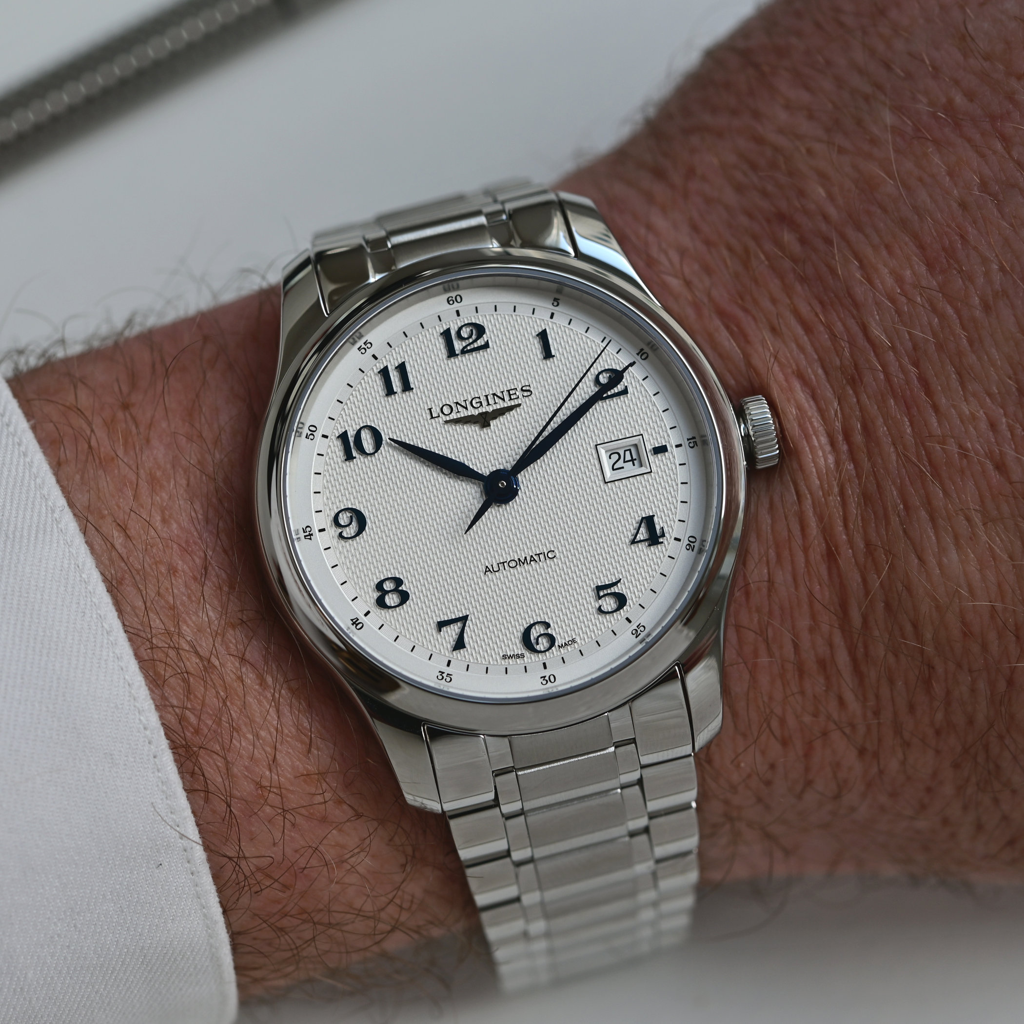 The redesigned Longines Master Collection worn on the wrist on a steel bracelet, a silver barleycorn dial with blue Arabic numerals, blued leaf hands and a date at three
