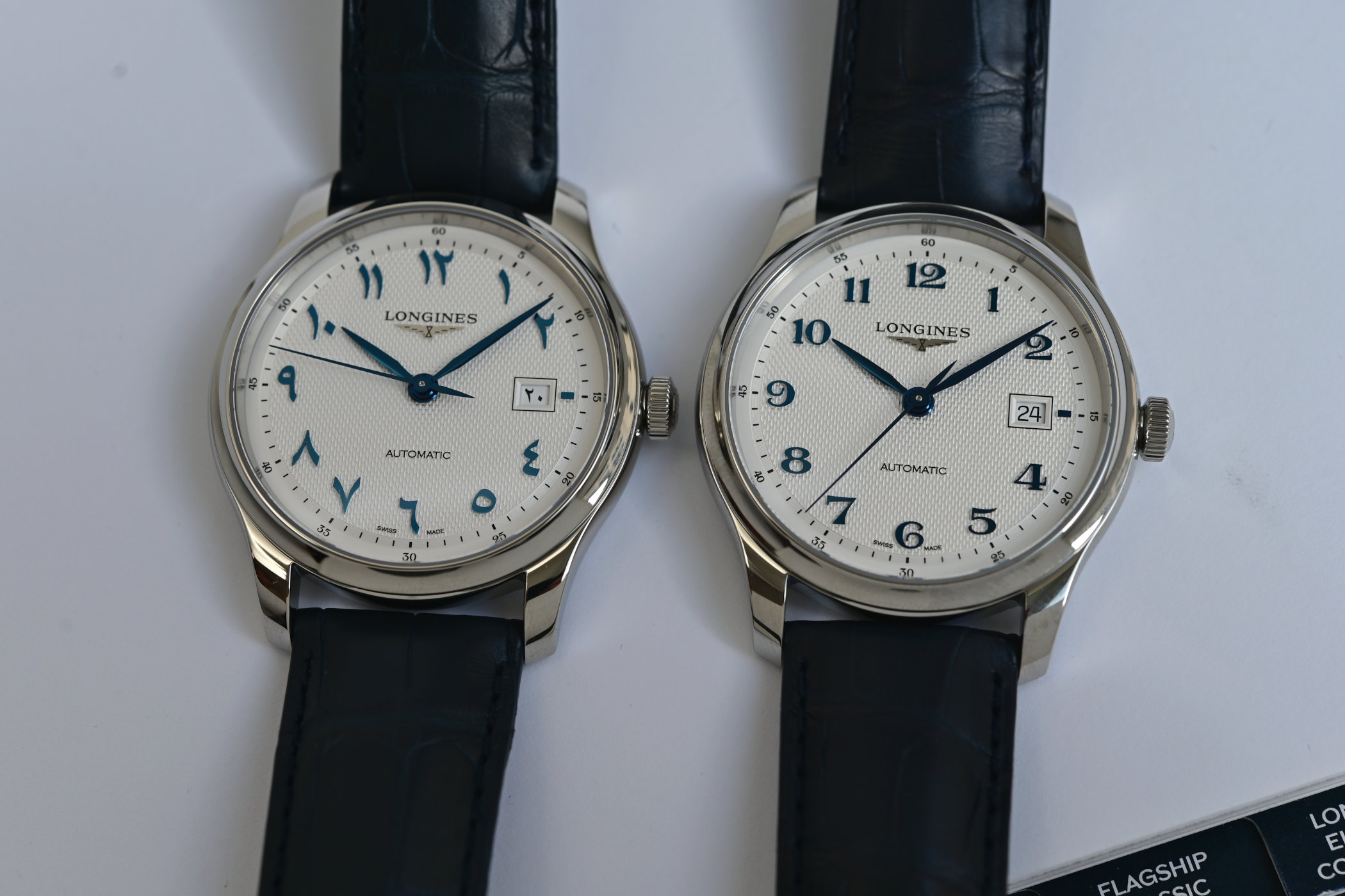 Two 41mm Master Collection dials side by side, the left with Eastern Arabic numerals and the right with Western Arabic numerals, both on silver barleycorn dials with blued hands on dark blue straps