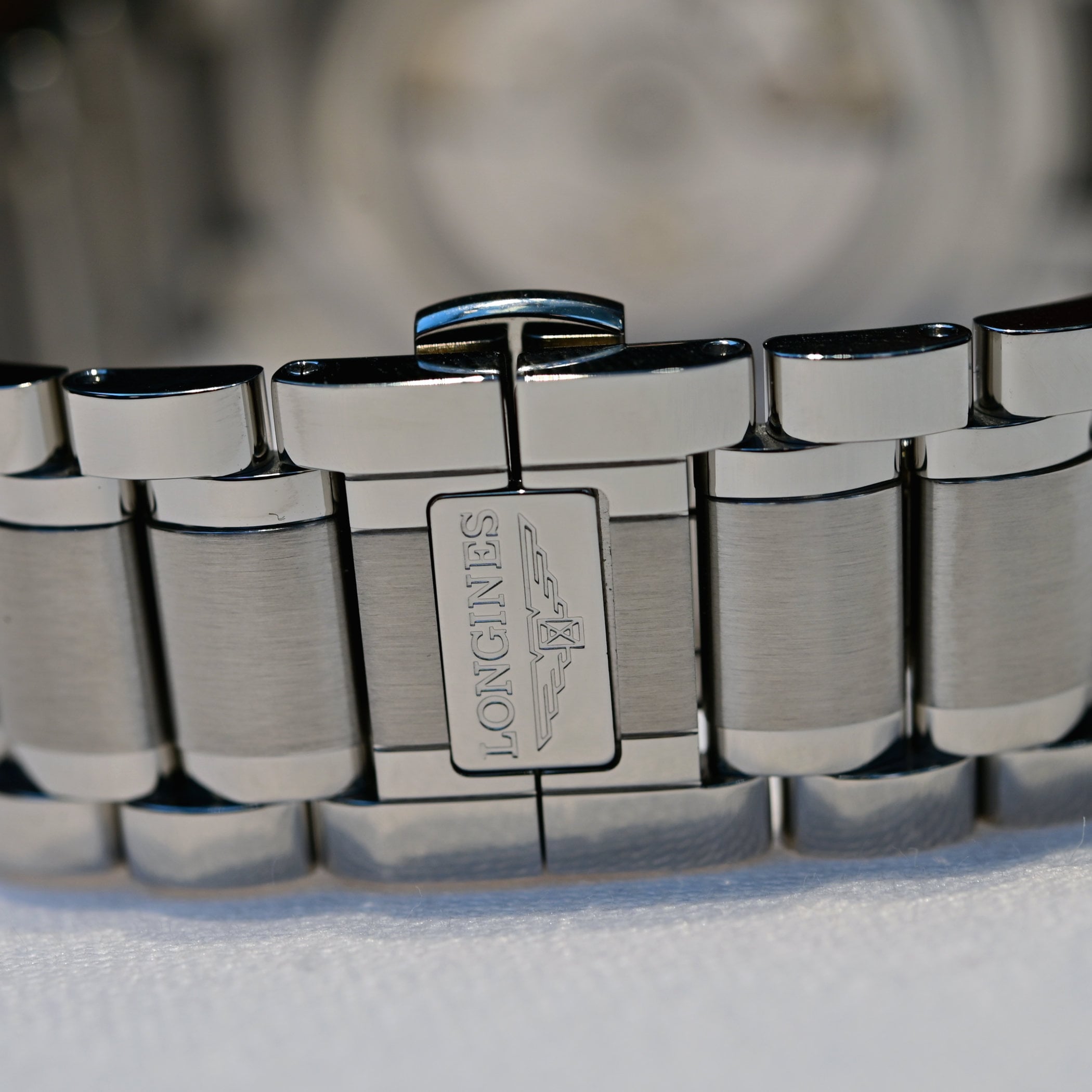 Close-up of the new Master Collection steel bracelet clasp, engraved with the Longines name and winged hourglass logo on a brushed and polished link