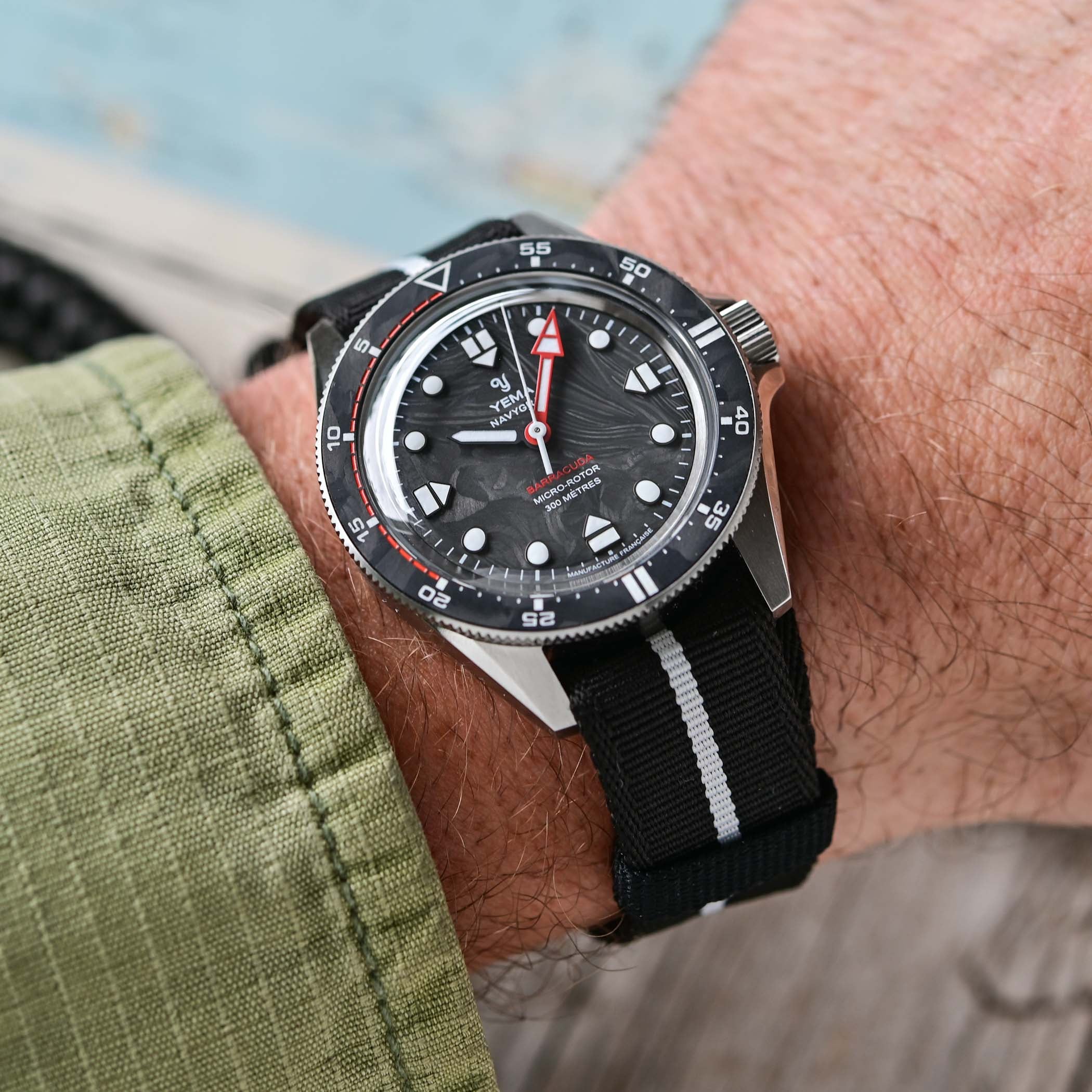 The Navygraf Barracuda worn on the wrist on a black NATO strap, three-quarter angle showing the brushed steel case, forged carbon bezel and domed sapphire