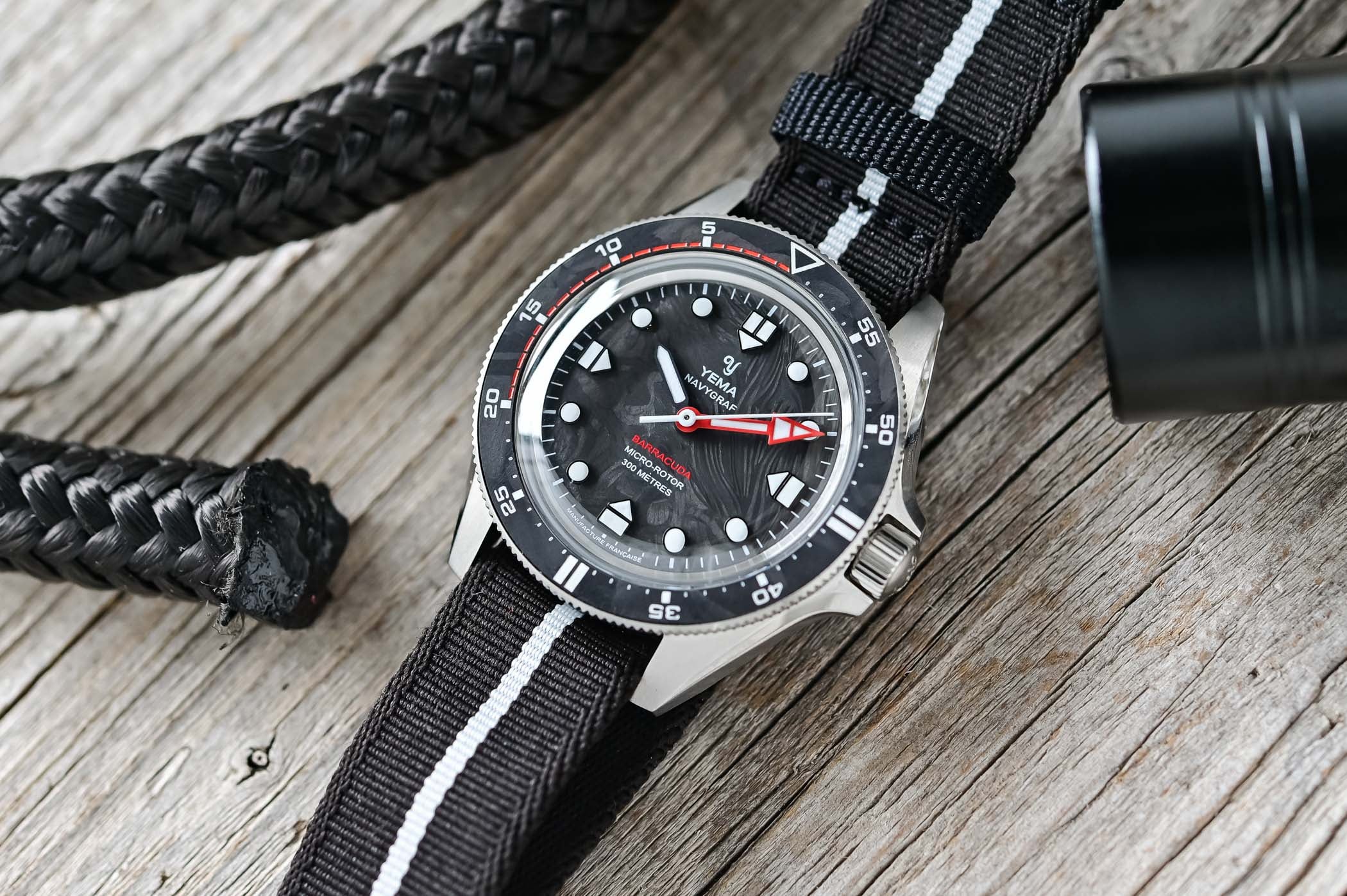 Yema Navygraf Barracuda CMM.20 on a black-and-white NATO strap, a marbled forged carbon dial reading BARRACUDA MICRO-ROTOR 300 METRES, a red arrow-tipped minute hand, white lume markers and a bezel whose first 20 minutes are red, in a brushed steel case