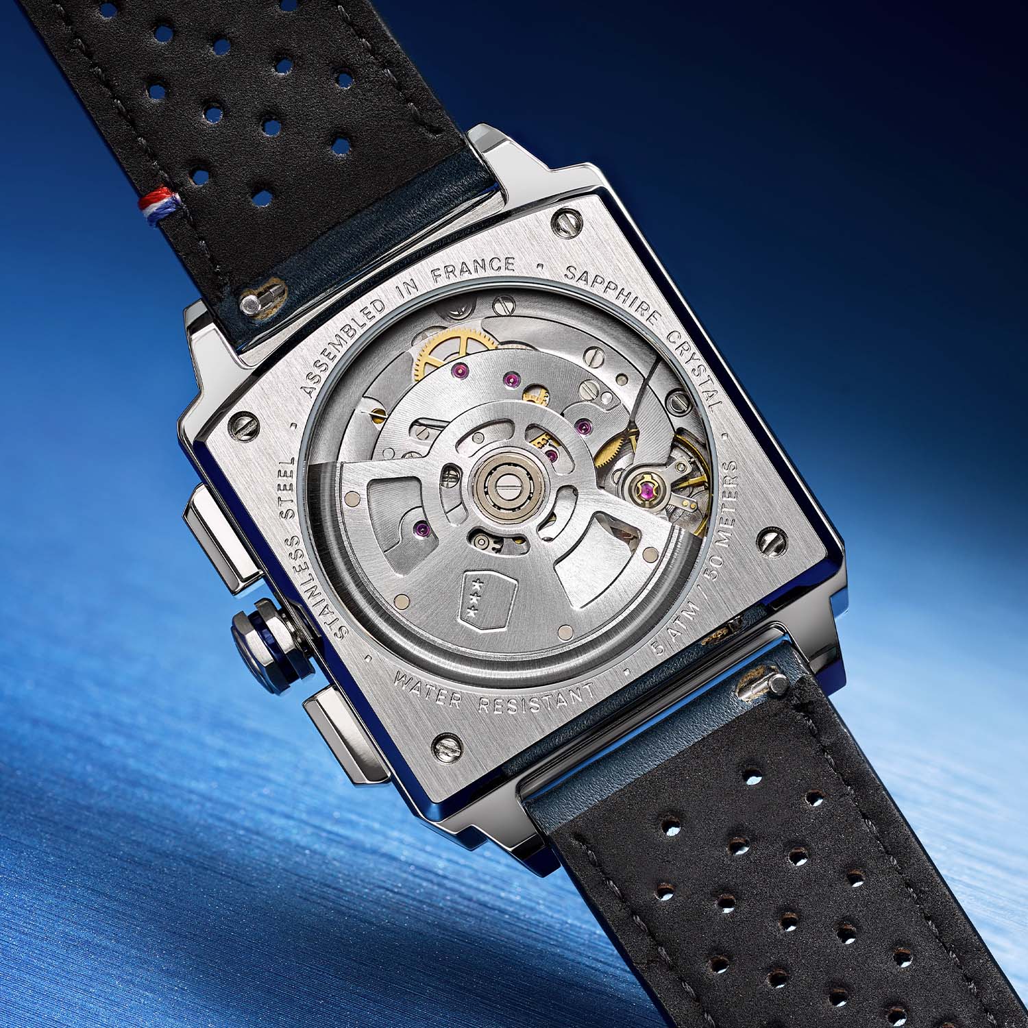 Caseback of the Serie-R Ice Blue, brushed steel with four screws and a round sapphire crystal showing the Peacock SL-4801 automatic movement and its rotor, engraved ASSEMBLED IN FRANCE, SAPPHIRE CRYSTAL, STAINLESS STEEL and WATER RESISTANT 5 ATM / 50 METERS