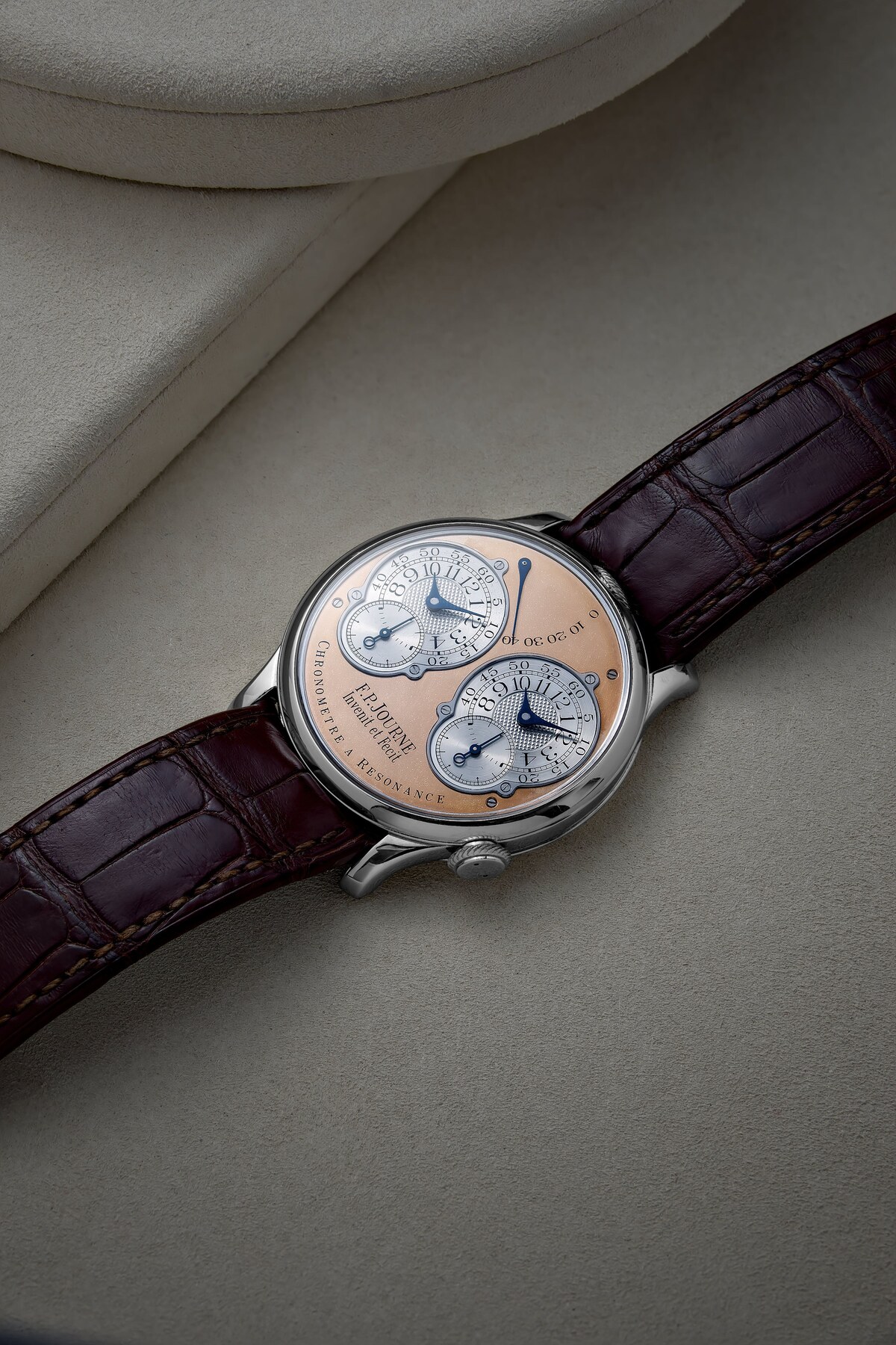F.P. Journe Chronomètre à Résonance 022/99R at a three-quarter angle on a cream ground, showing the platinum case, pink gold dial, two silver-toned subdials with blued hands and the seconds scale at the top, on a brown alligator strap