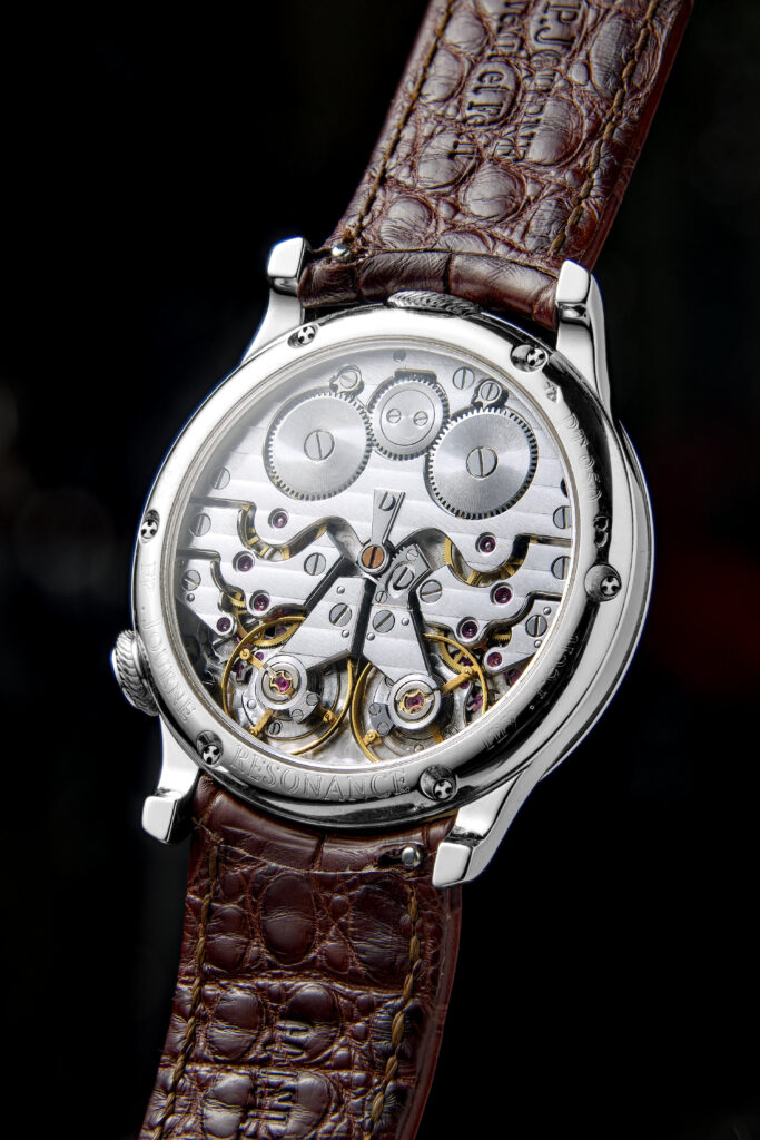 Caseback of the Résonance seen through the sapphire, the brass movement with its two going trains and two balance wheels set side by side, and RESONANCE engraved on the case ring