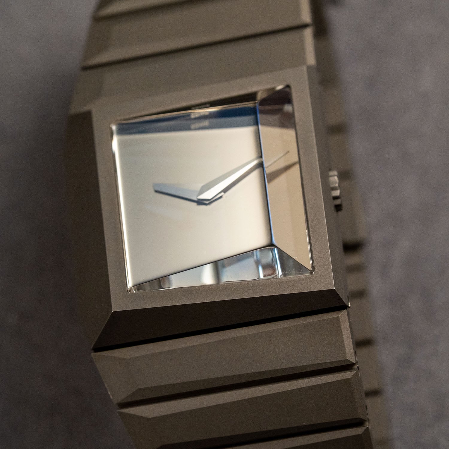 Close-up of the Toledano & Chan Breutalist, the plain mirror dial and two faceted hands under the angular faceted sapphire crystal, set in a bead-blasted grade 5 titanium case