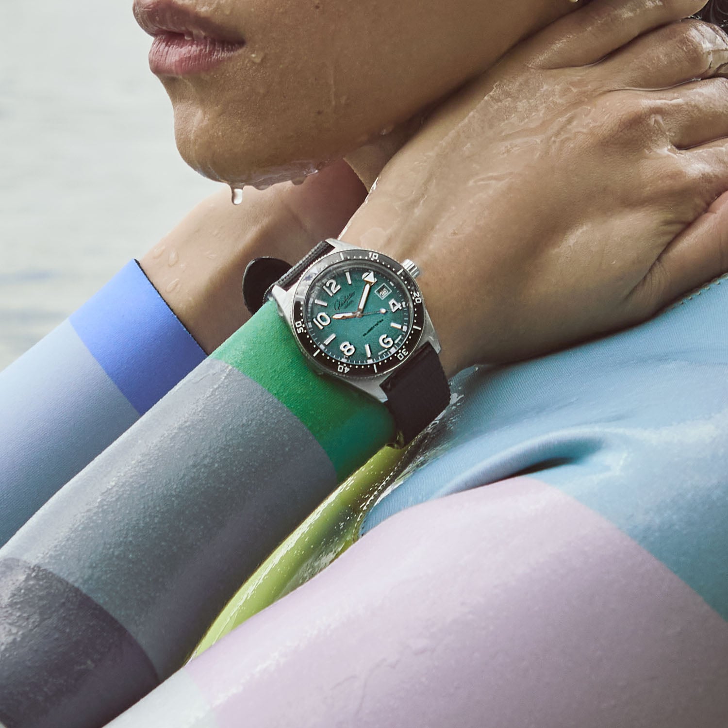 The SeaQ Northern Tide worn at the water's edge on a black strap, the turquoise dial catching the light