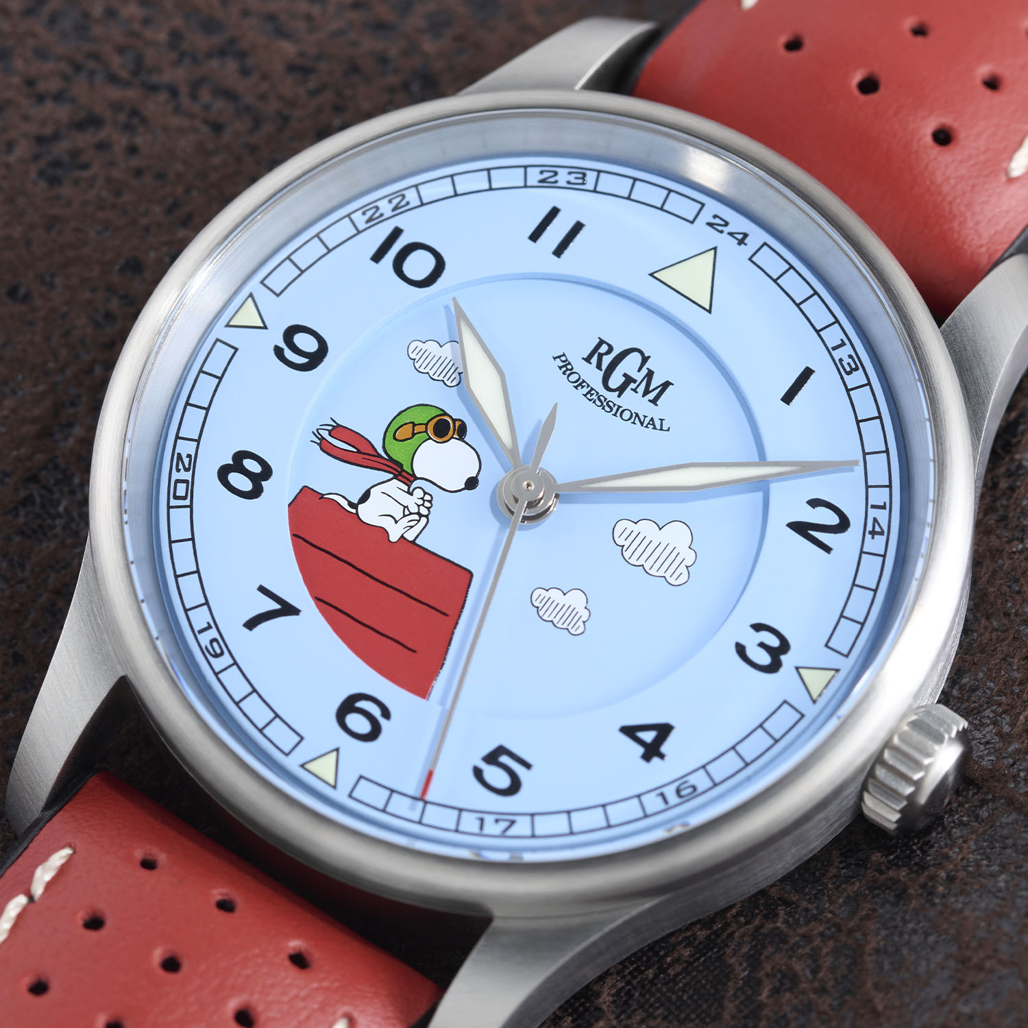The more affordable RGM Model 151 Flying Ace with the matte light-blue metal dial, the same Snoopy artwork and cloud markers and luminous hands, shown on a red perforated leather strap