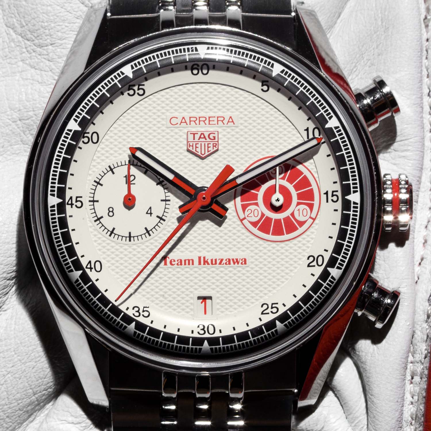 Macro of the TAG Heuer Carrera x Team Ikuzawa dial, white Clou de Paris texture with a red central chronograph hand, a 12-hour counter at 9, the red Roadmaster-style 30-minute counter at 3 and the date at 6 below the Team Ikuzawa signature