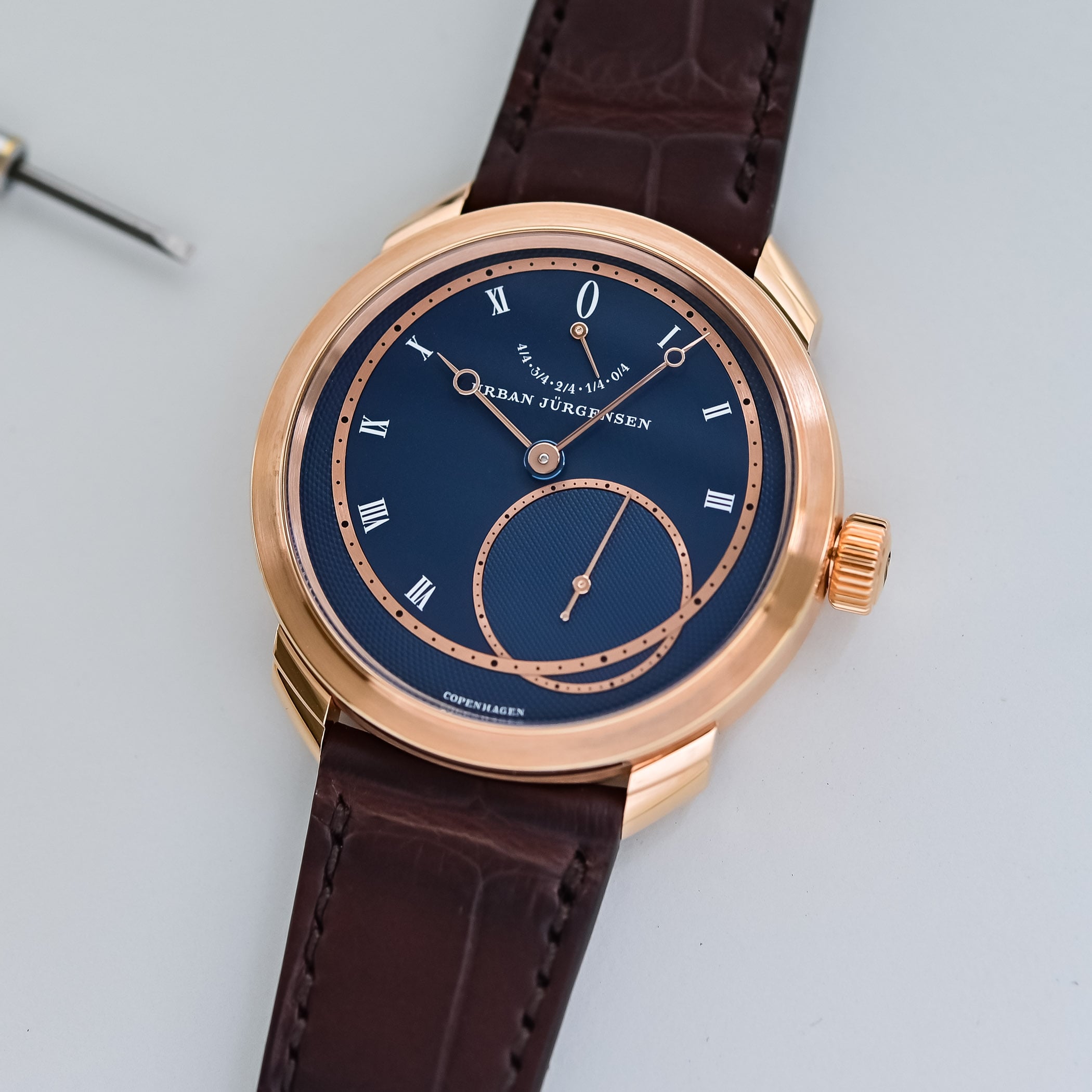 Angled view of the rose gold UJ-2 with a deep blue dial, circular Grain d'orge and Clous de Paris guilloché, offset hours-and-minutes ring, power reserve scale marked 4/4 to 0/4 at 12 and Roman numerals