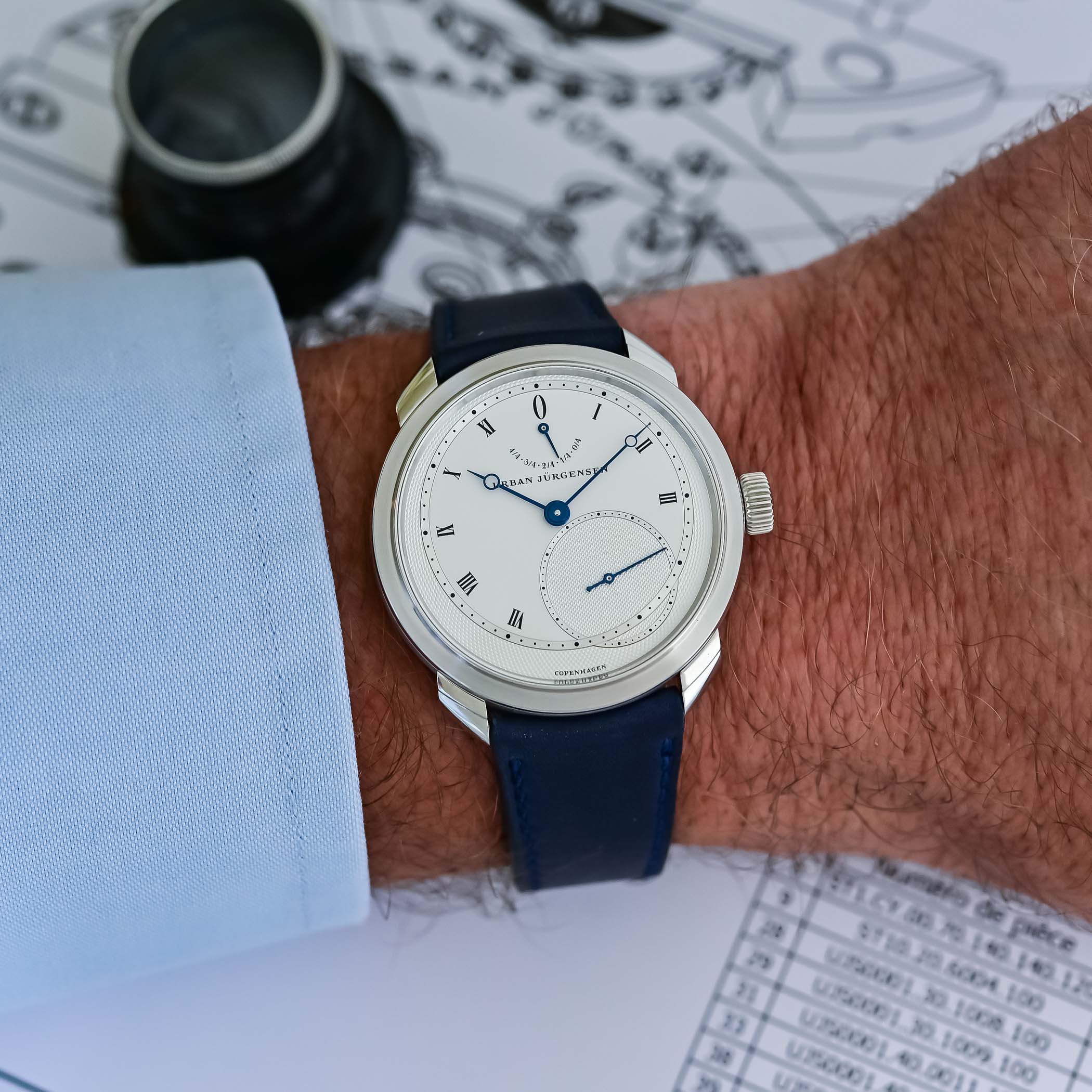 The platinum UJ-2 with a white-silver guilloché dial, black Roman numerals and blued hands worn on the wrist on a dark blue strap