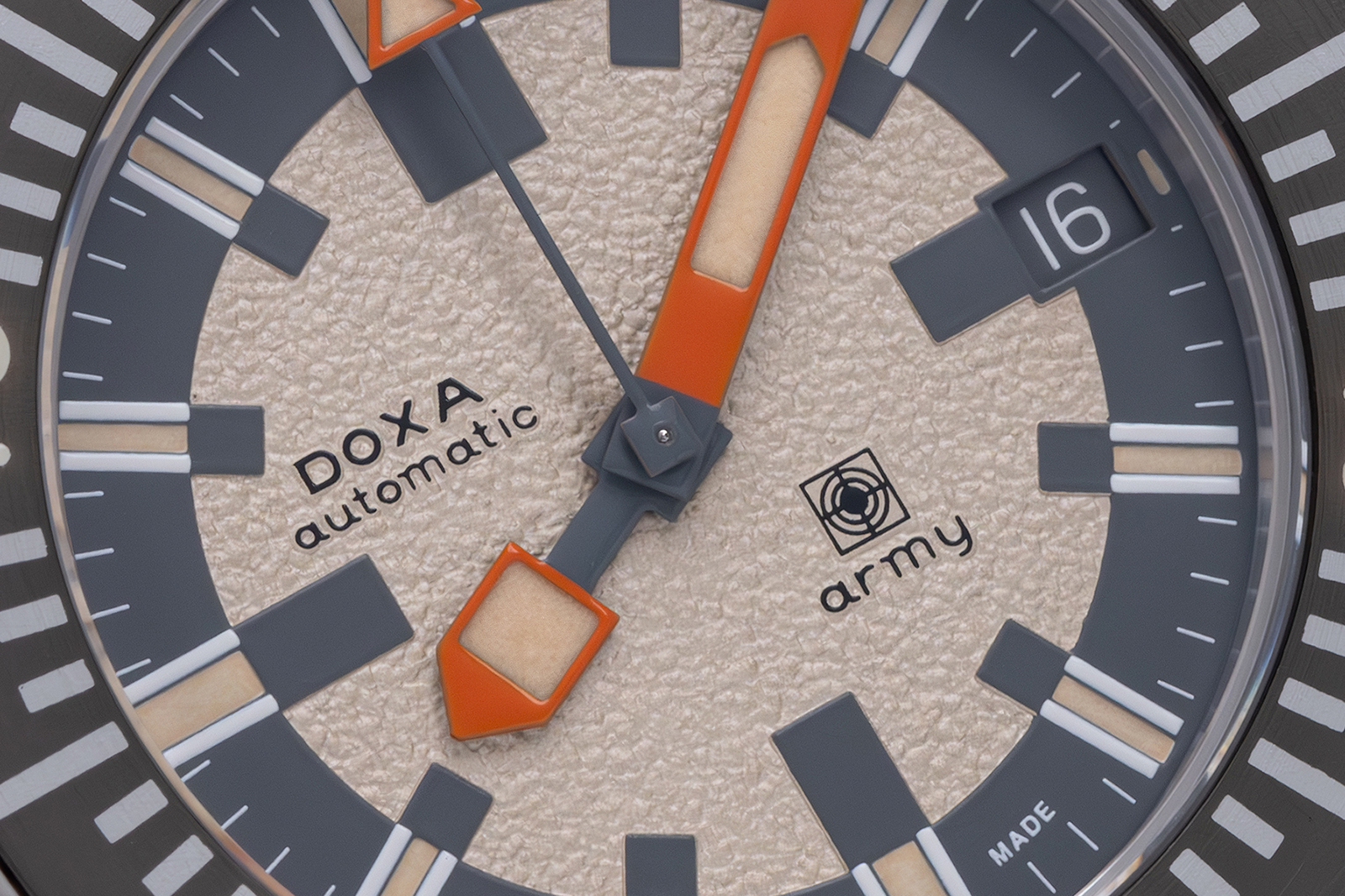 Macro of the DOXA SUB Army 200T for Hodinkee dial, sand-coloured granular centre with a grey chapter ring, grey markers with aged lume, orange hands and the date at 3, marked DOXA automatic army