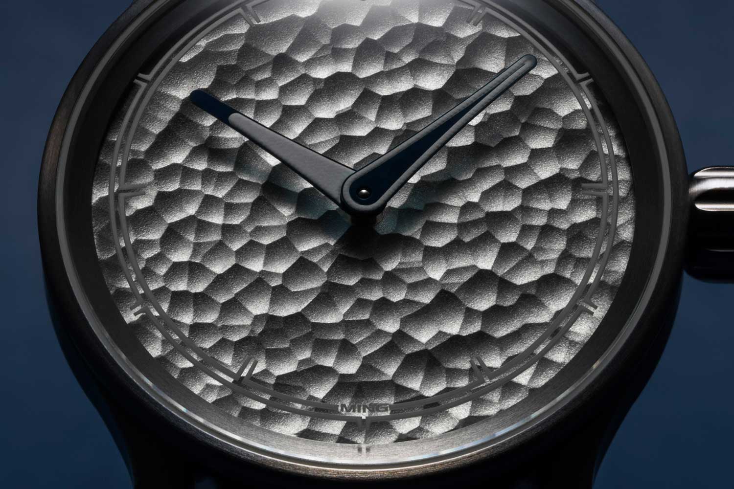 Macro of the MING 37.06 Royal Selangor dial, hammered silver-grey pewter surface with recessed hour markers, blued baton hands and MING printed at 6 o'clock