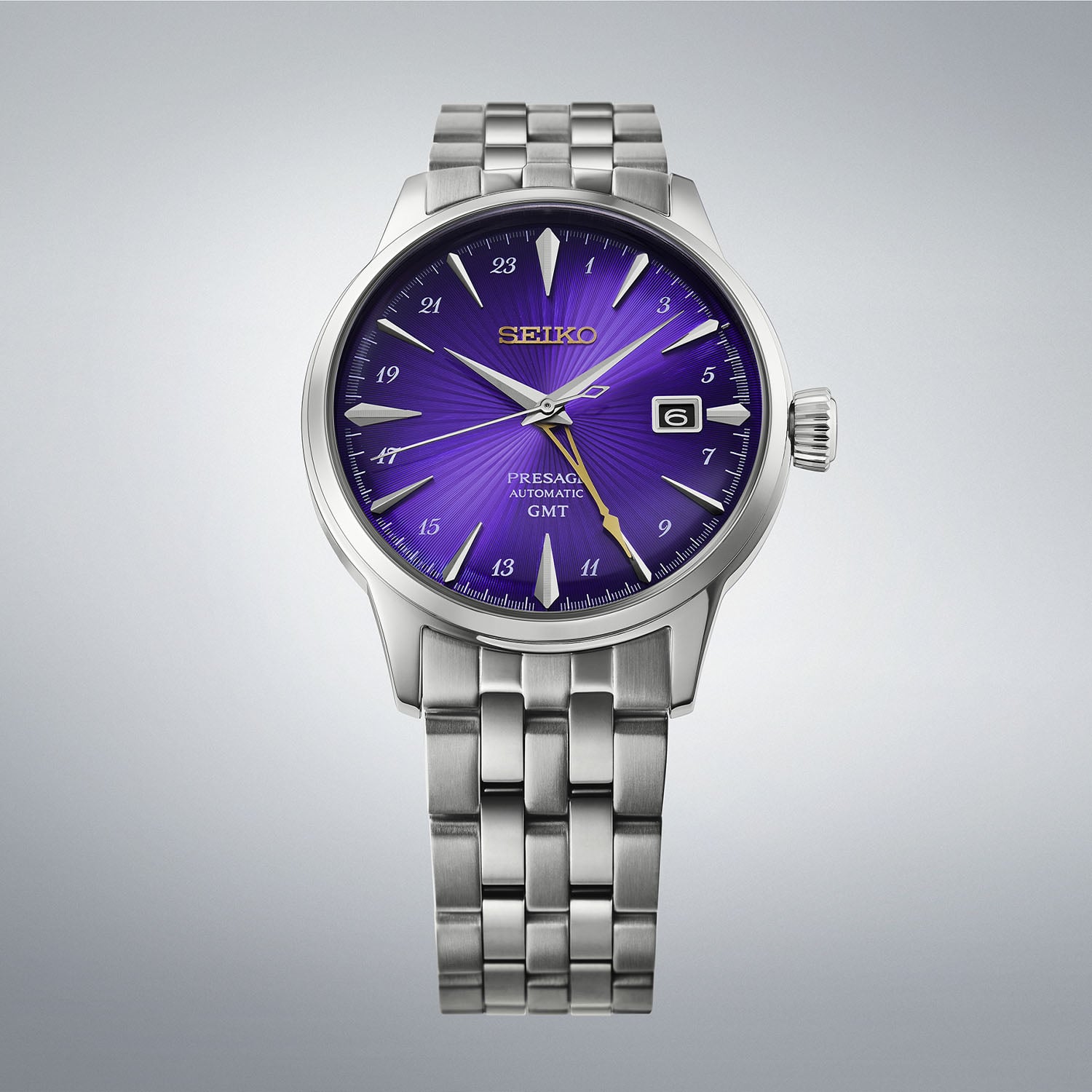 The Seiko Presage Cocktail Time GMT HCB006 with a vibrant translucent purple dial and radial pattern, 24-hour numerals, a gold GMT hand and a date window, on a steel bracelet