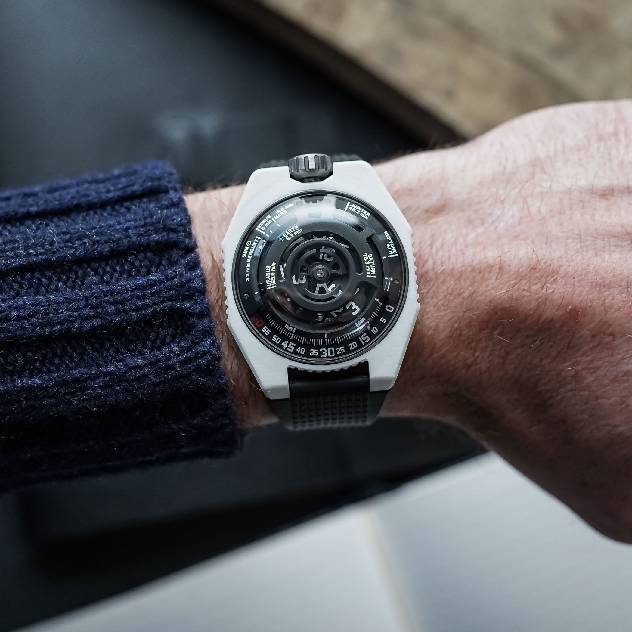 Caseback of the Urwerk UR-100V Lightspeed Ceramic in DLC-treated titanium, the black skeletonised Windfänger planetary turbine rotor visible through the sapphire with the engravings UR-100VC, Planetary Turbine and Swiss Made