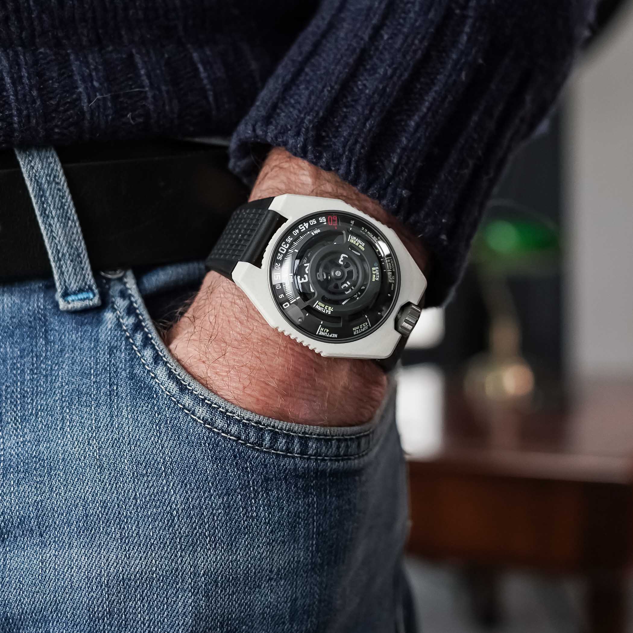 The Urwerk UR-100V Lightspeed Ceramic on the wrist, the white ceramic case and black rubber strap seen from a low angle showing the crown at 12 o'clock