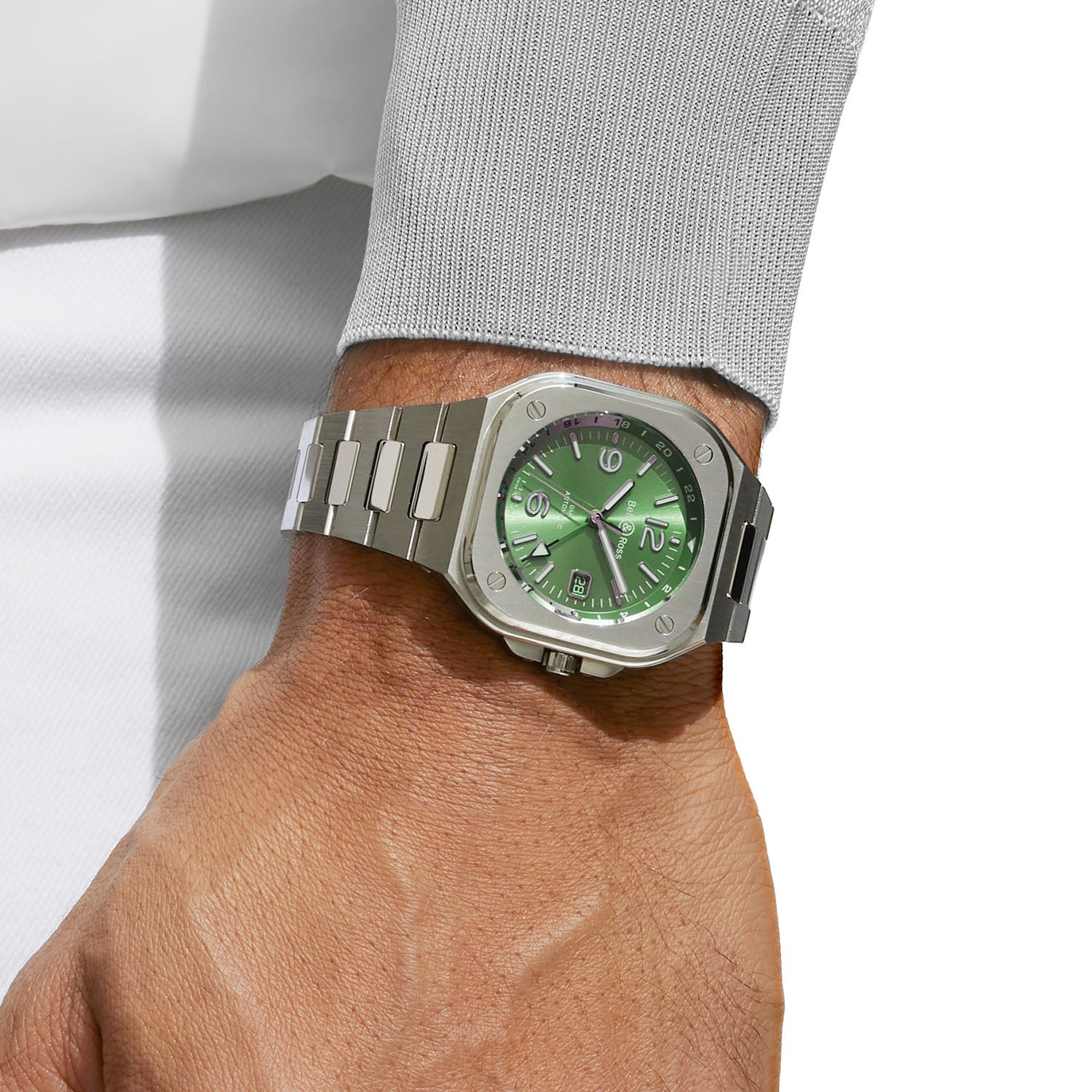 The BR-05 GMT Green Steel worn on the wrist on its integrated steel bracelet, the green dial and 24-hour scale visible under a shirt cuff