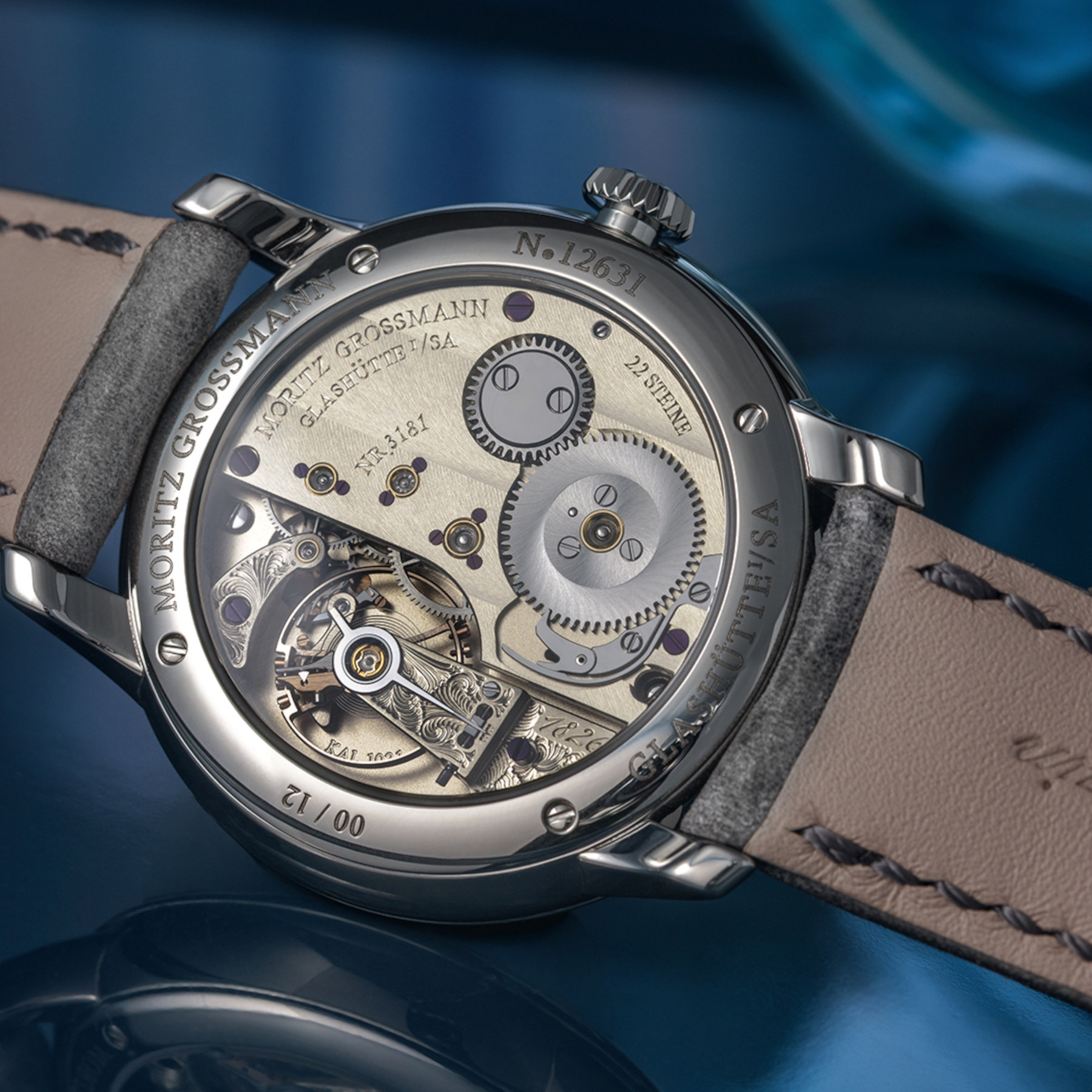 Caseback of the Moritz Grossmann Tefnut 36 showing the hand-wound calibre 102.1, German silver plate with wide Glashutte striping, a hand-engraved balance cock, gold chatons and the 00/12 engraving of the twelve-piece edition