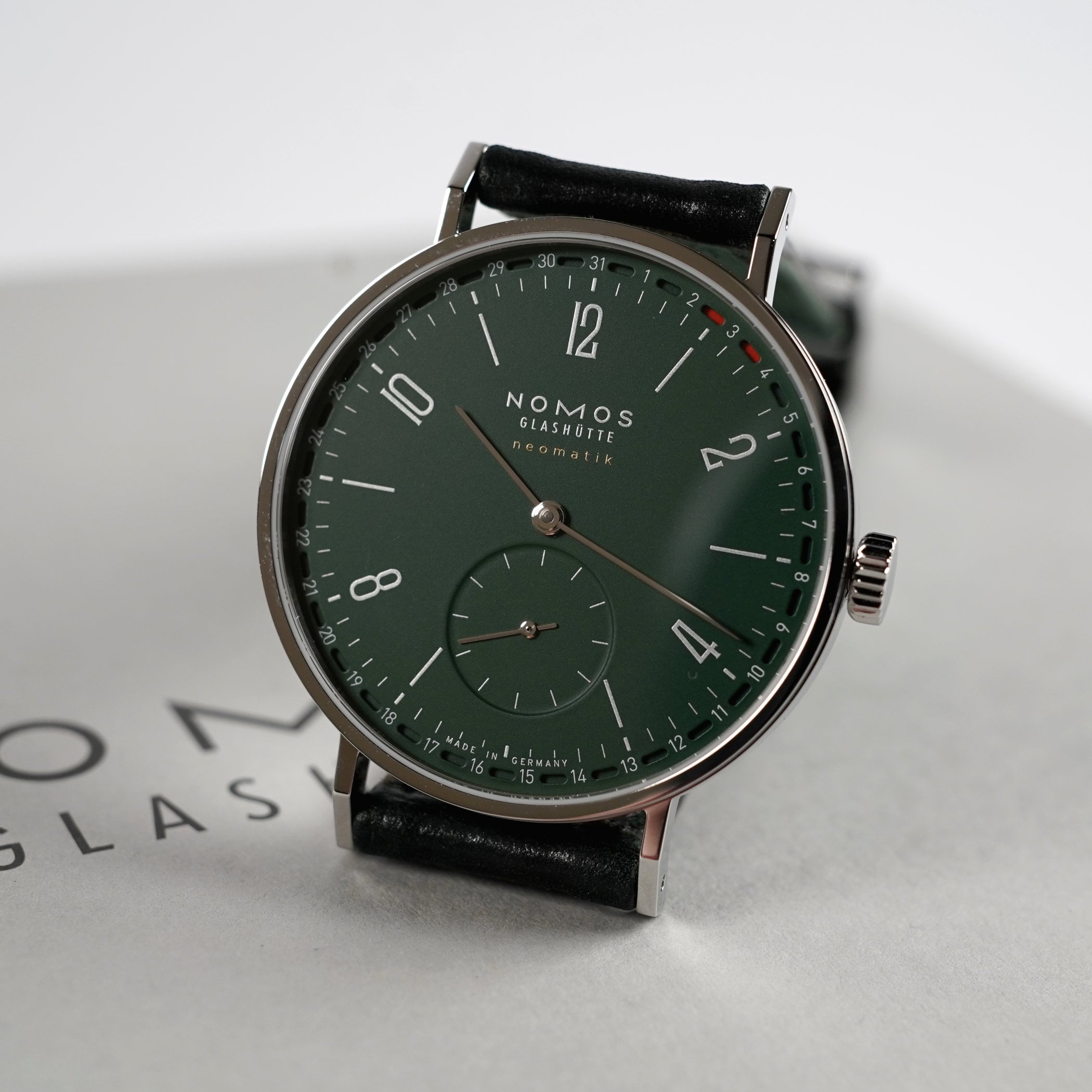 The forest-green Nomos Tangente Neomatik 38 Update, reference 148, at an angle showing silver indices and inscriptions, rhodium-plated hands and the red date markers on the peripheral ring